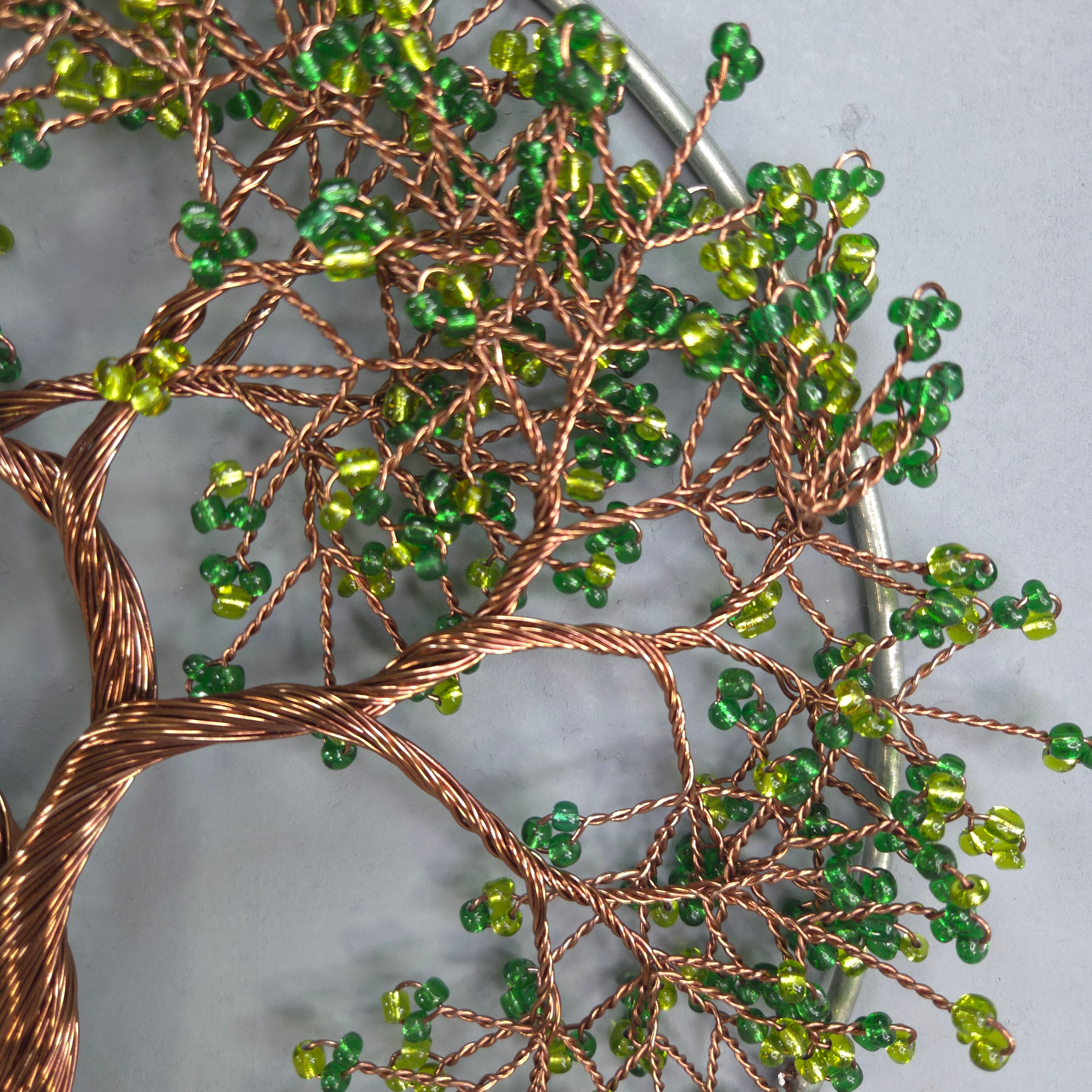 Decorative wall art of a tree with green beads on a gray background