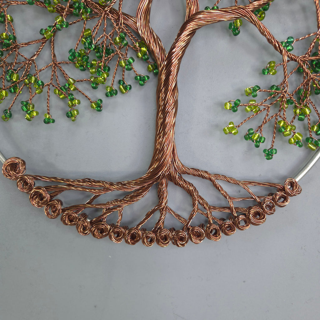 Decorative wall art with copper wire and green beads on a gray background