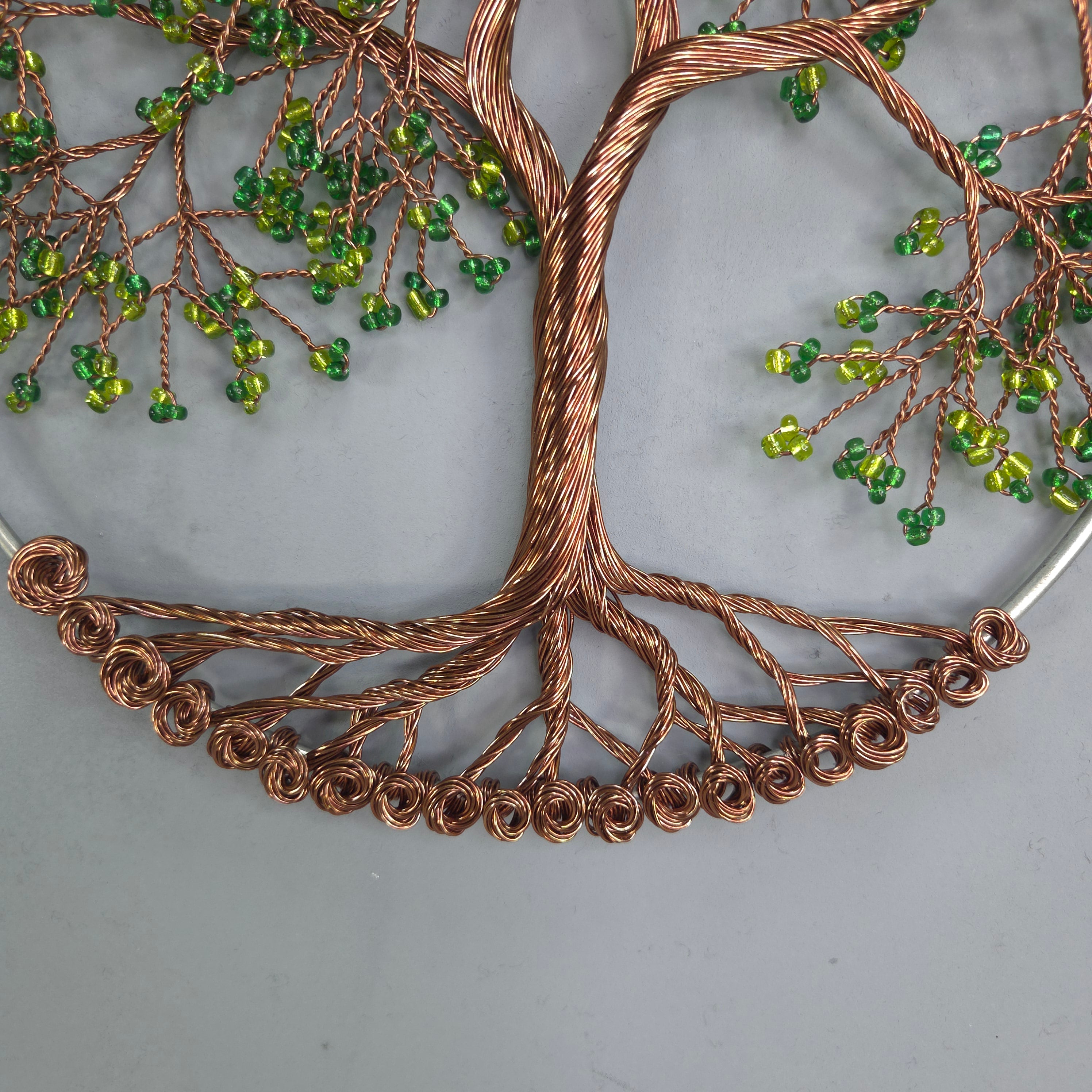 Decorative wall art with copper wire and green beads on a gray background