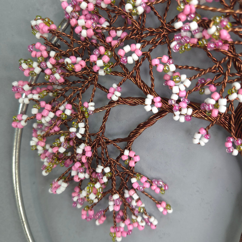 Decorative branch with pink, white, and green beads on a gray background