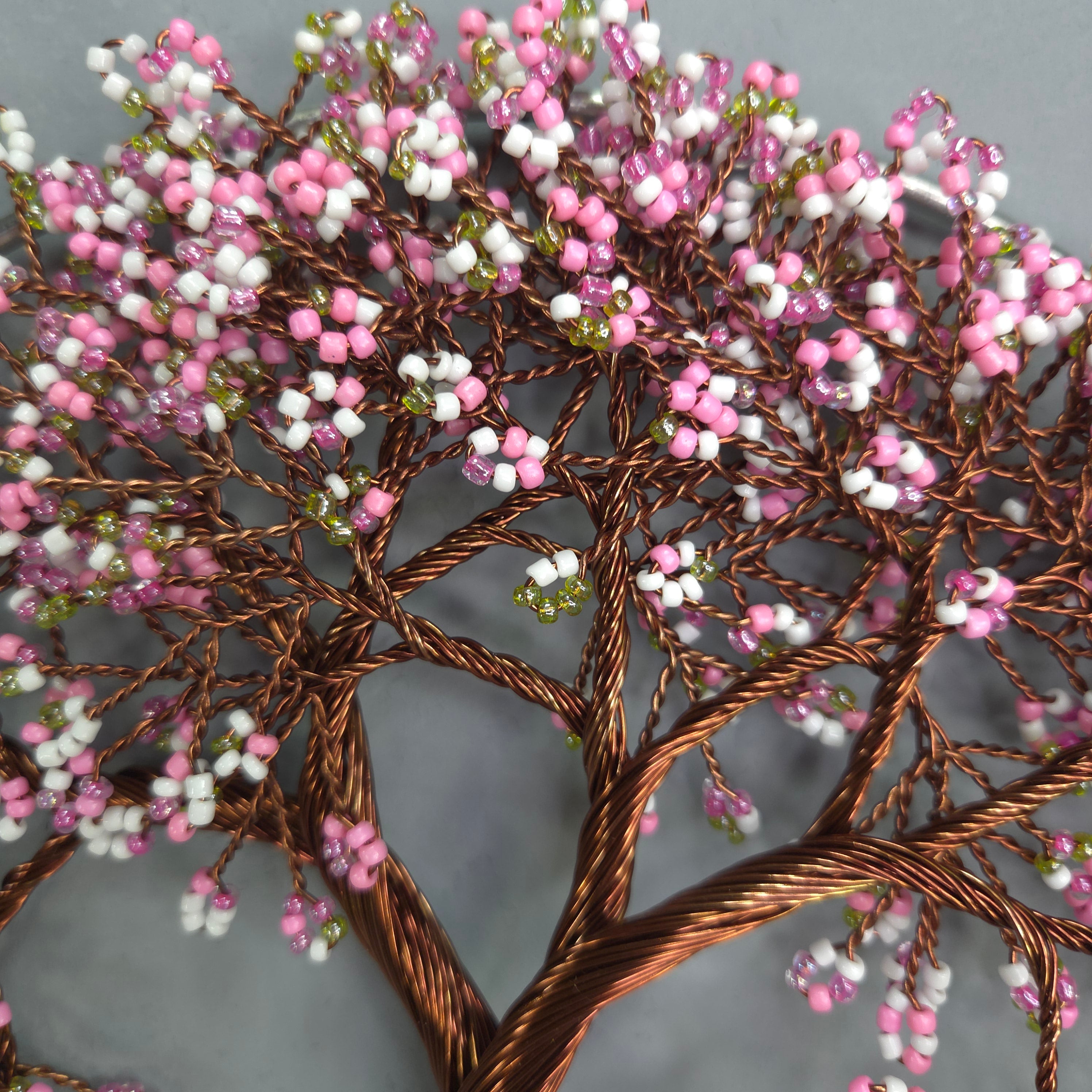 Decorative tree sculpture with pink and white beads on a gray background