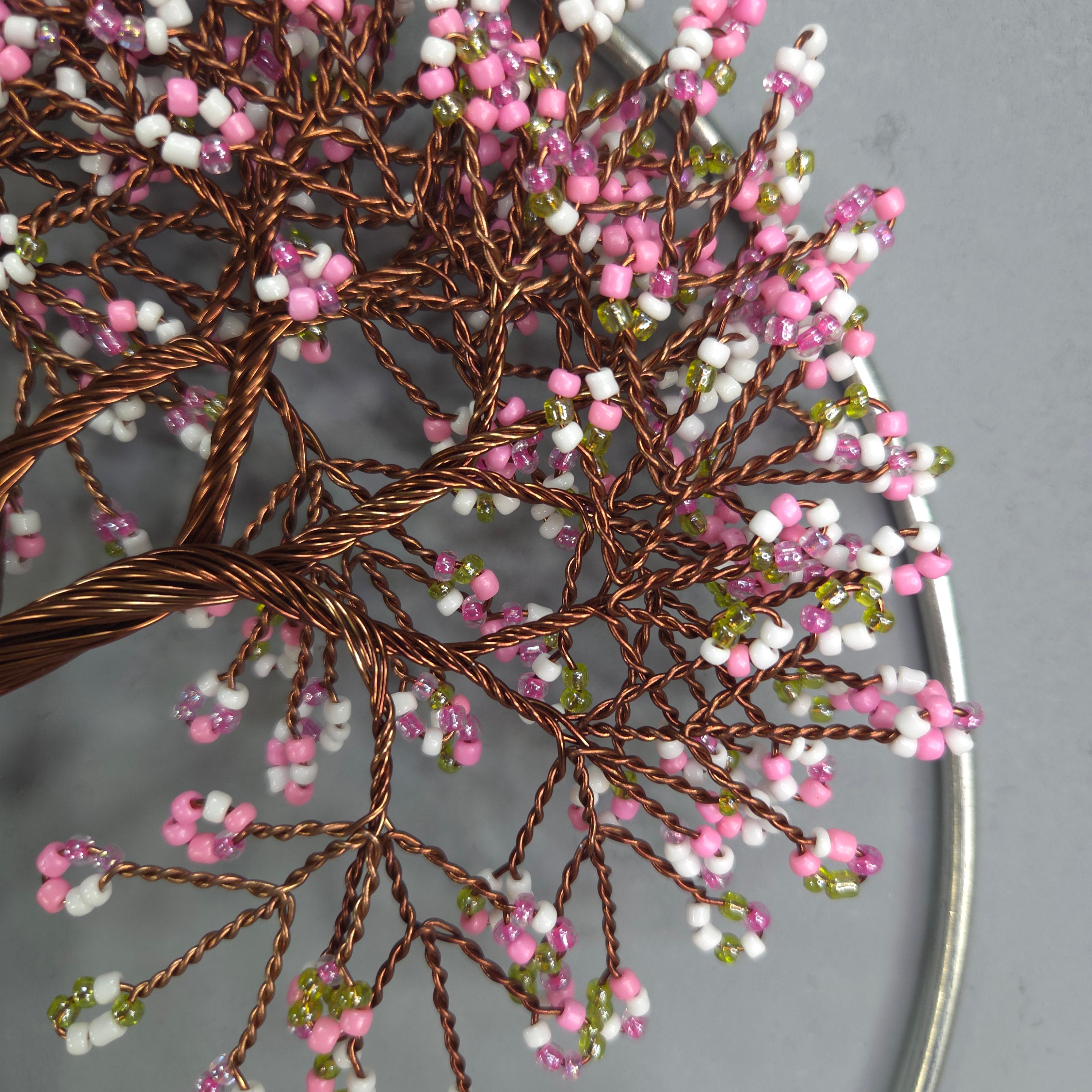 Decorative branch with pink, white, and green beads on a gray background