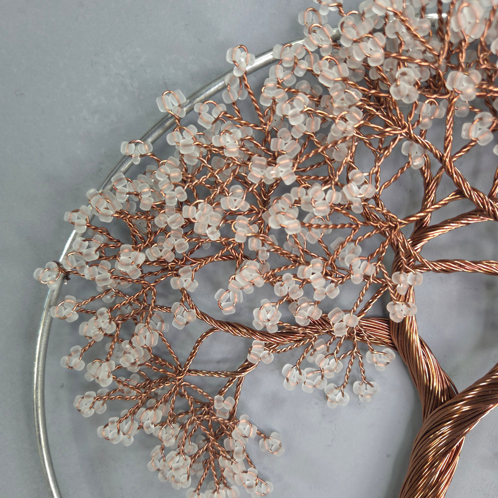 Decorative wreath with copper wire and clear beads on a gray background
