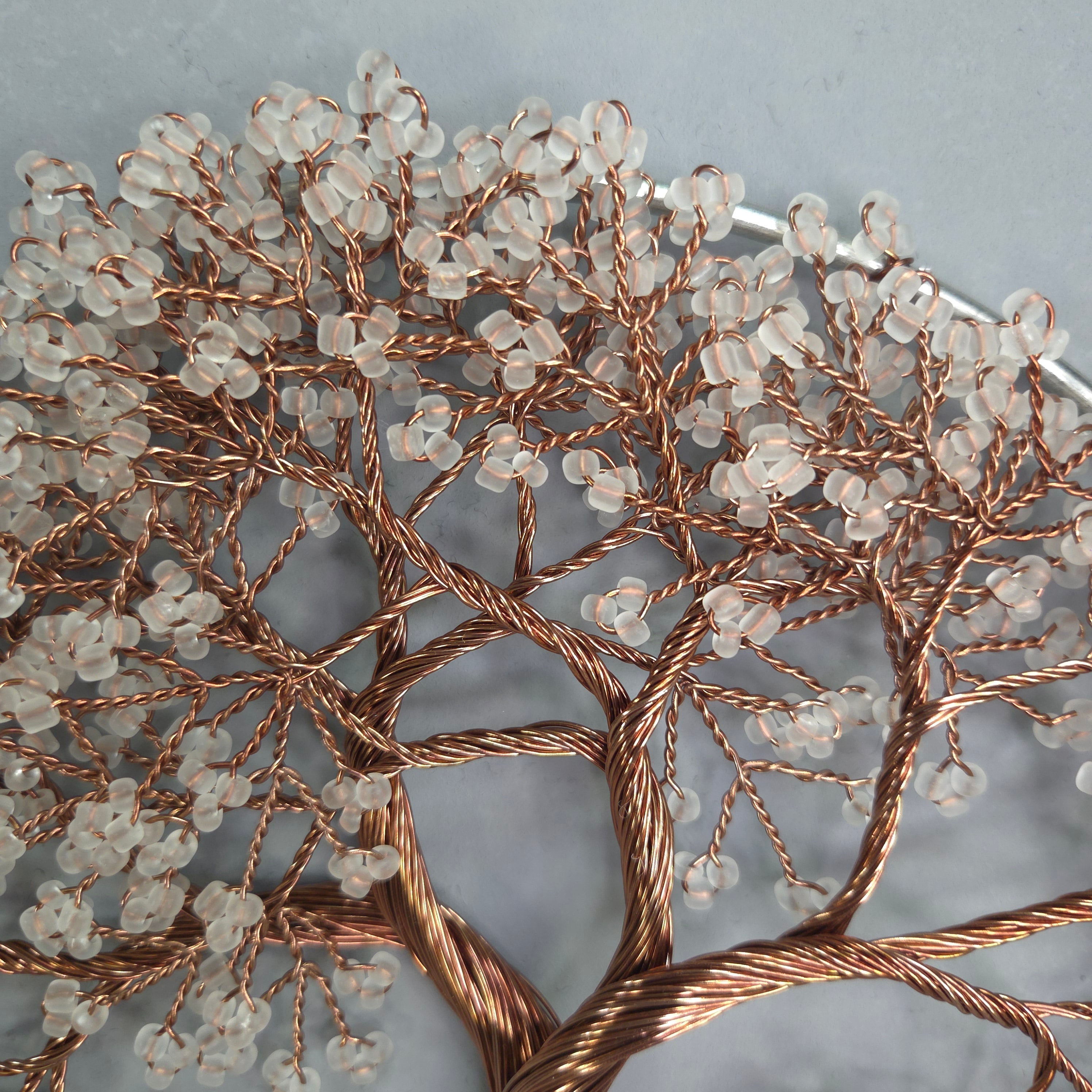 Decorative wall art with copper branches and clear beads on a gray background