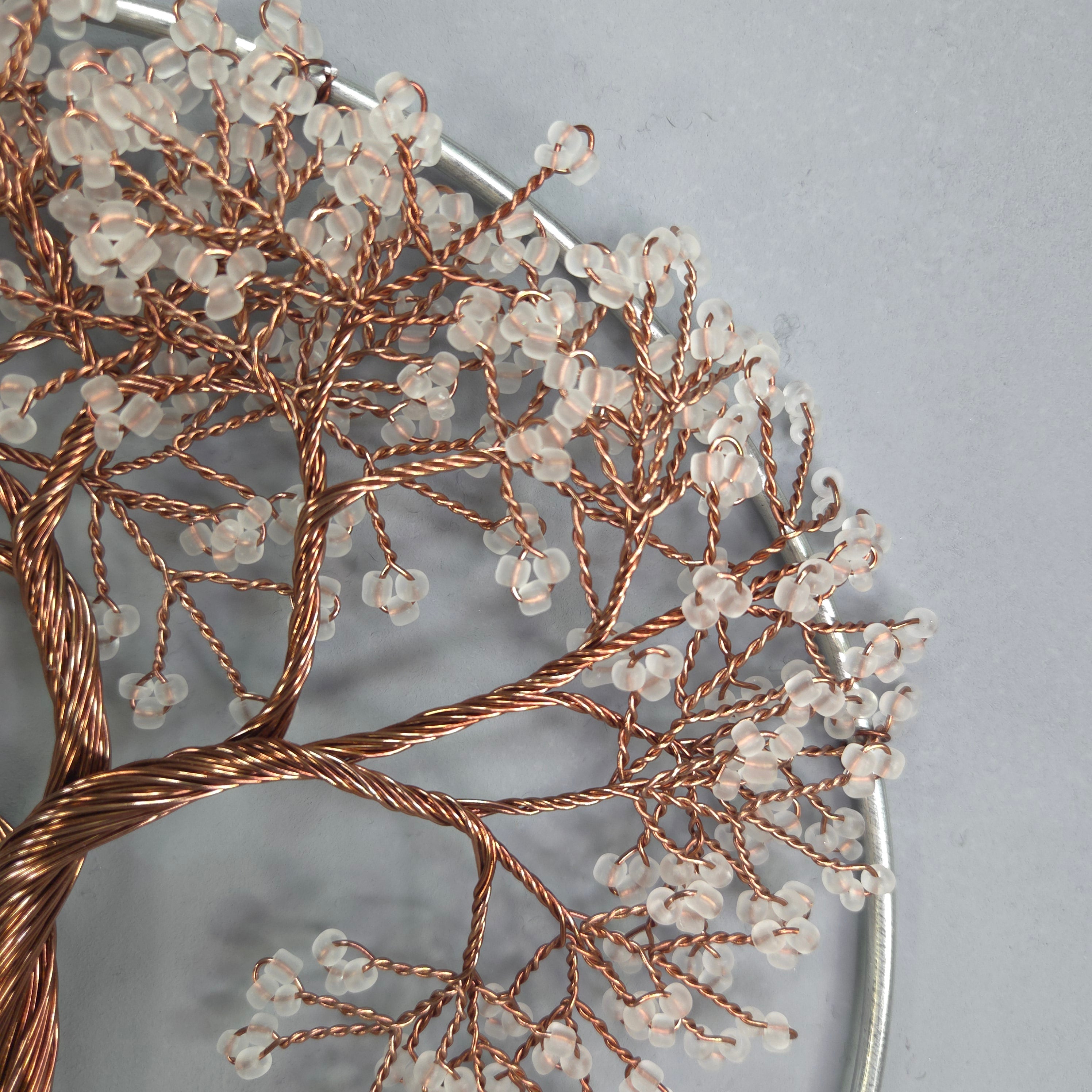 Decorative tree sculpture with copper branches and clear beads on a gray background
