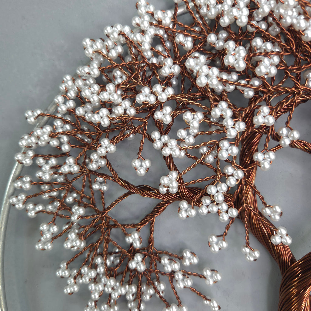 Decorative branch with white berries and copper wire on a gray background