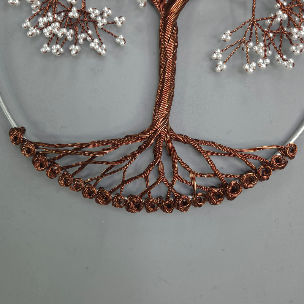 Decorative copper wire tree with small white beads on a gray background