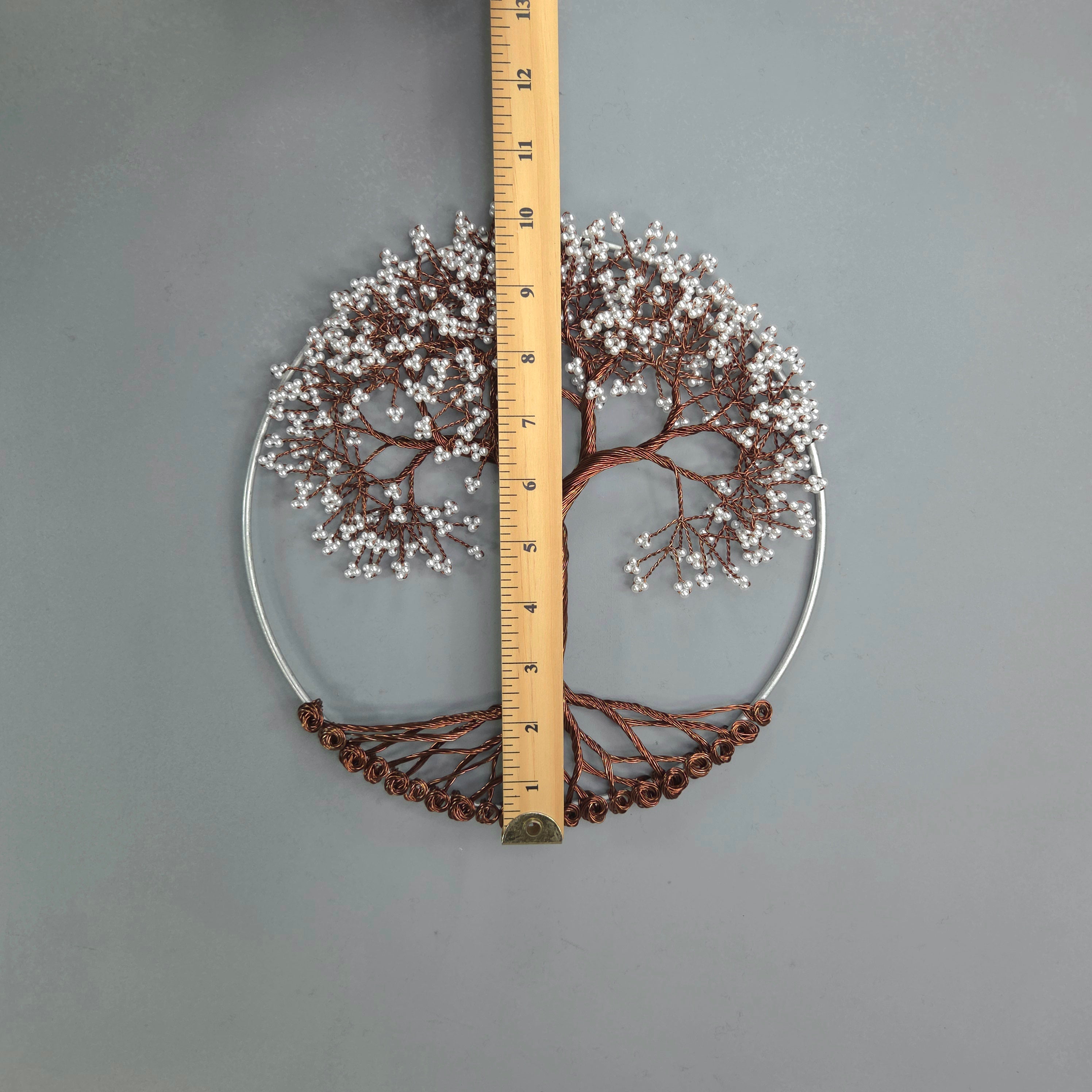 Decorative wall art with tree design and measurement ruler on a gray background