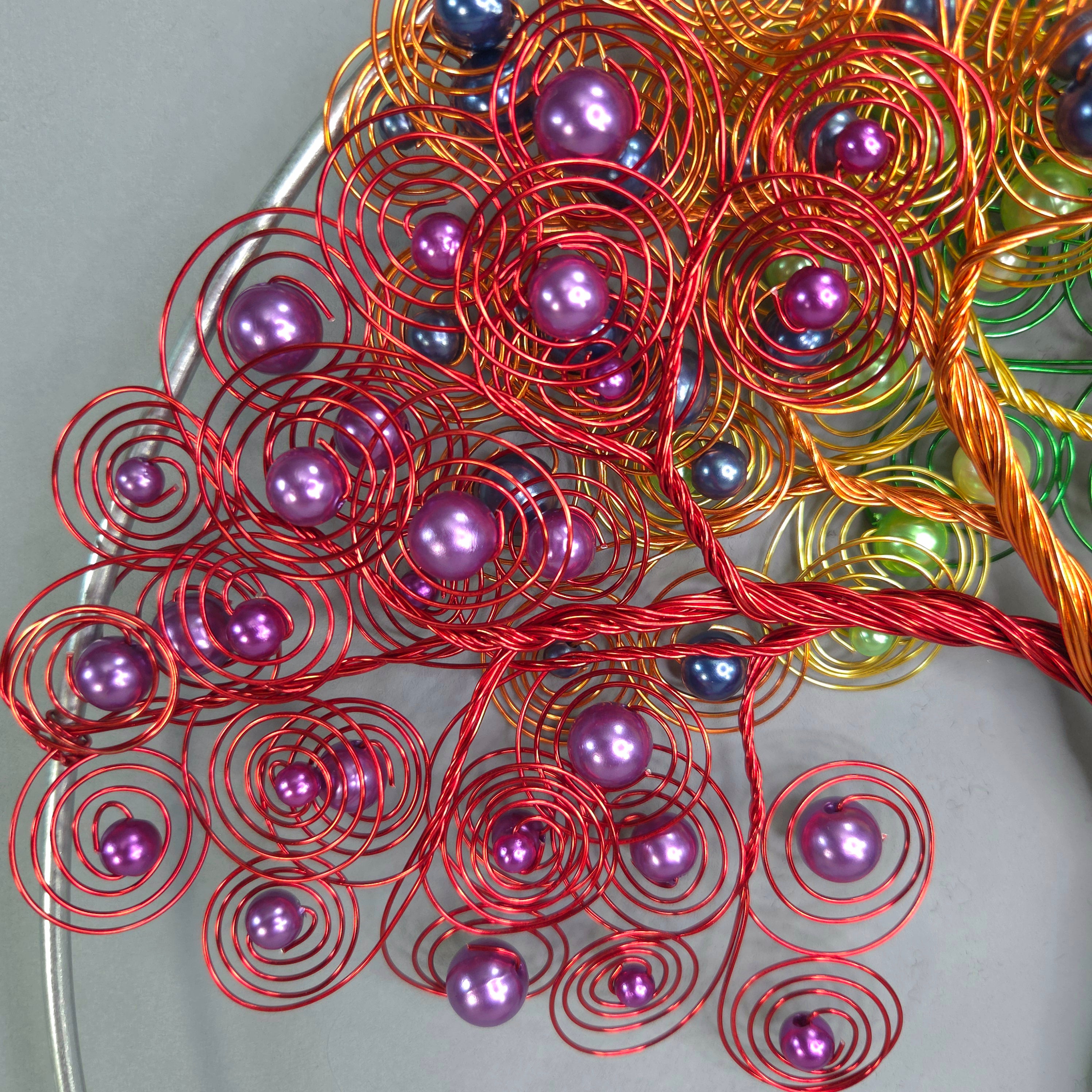 Decorative metal sculpture with purple beads on a gray background