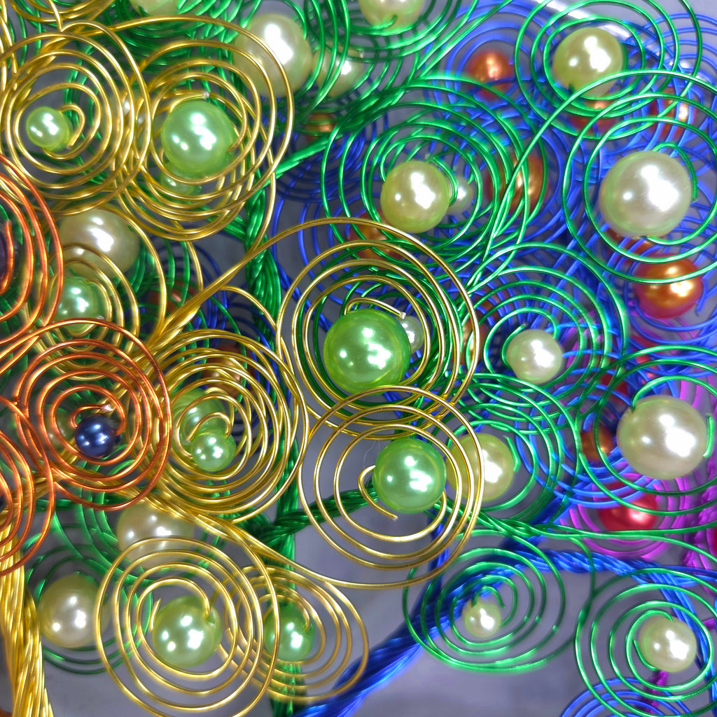 Decorative metal tree with green beads against a colorful background
