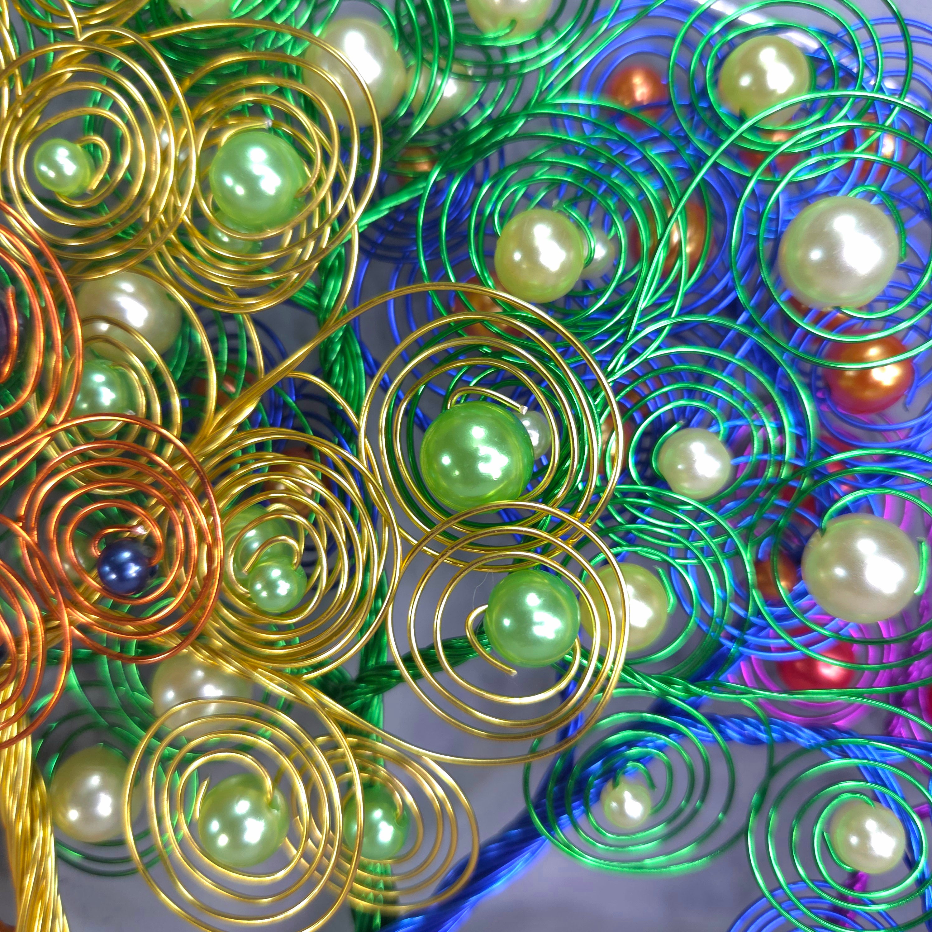 Decorative metal tree with green beads against a colorful background