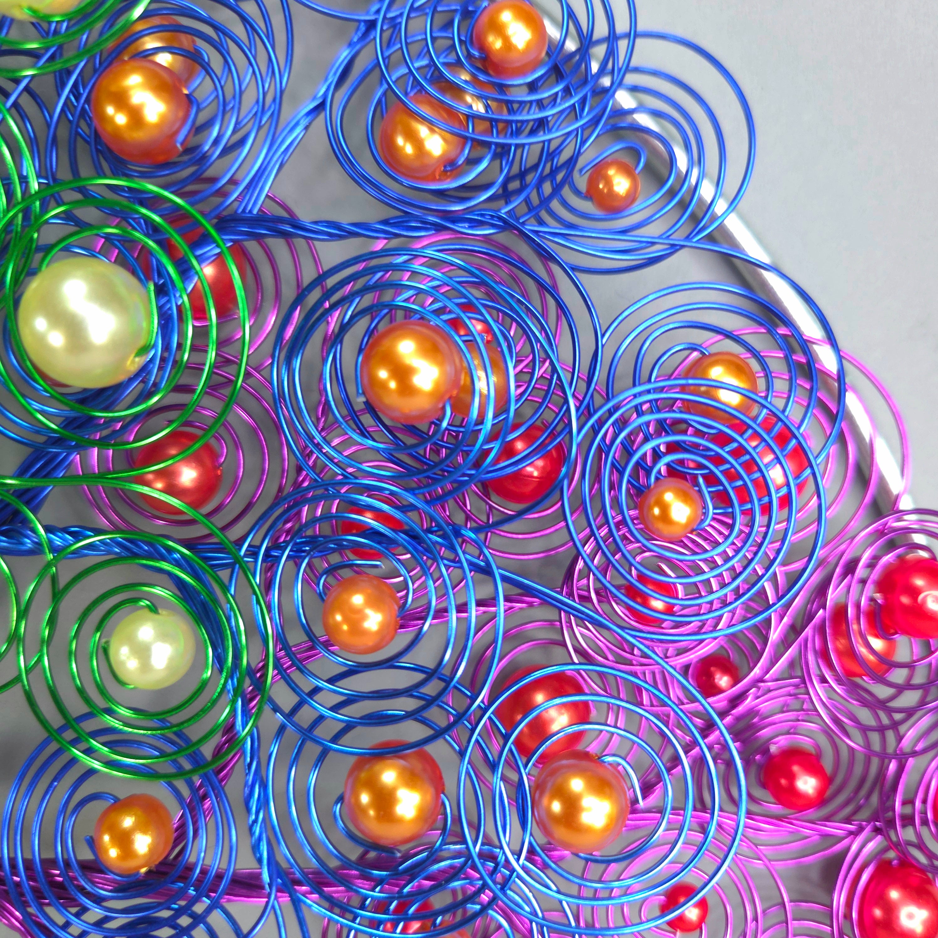 Colorful metal coils with spherical beads on a gray background