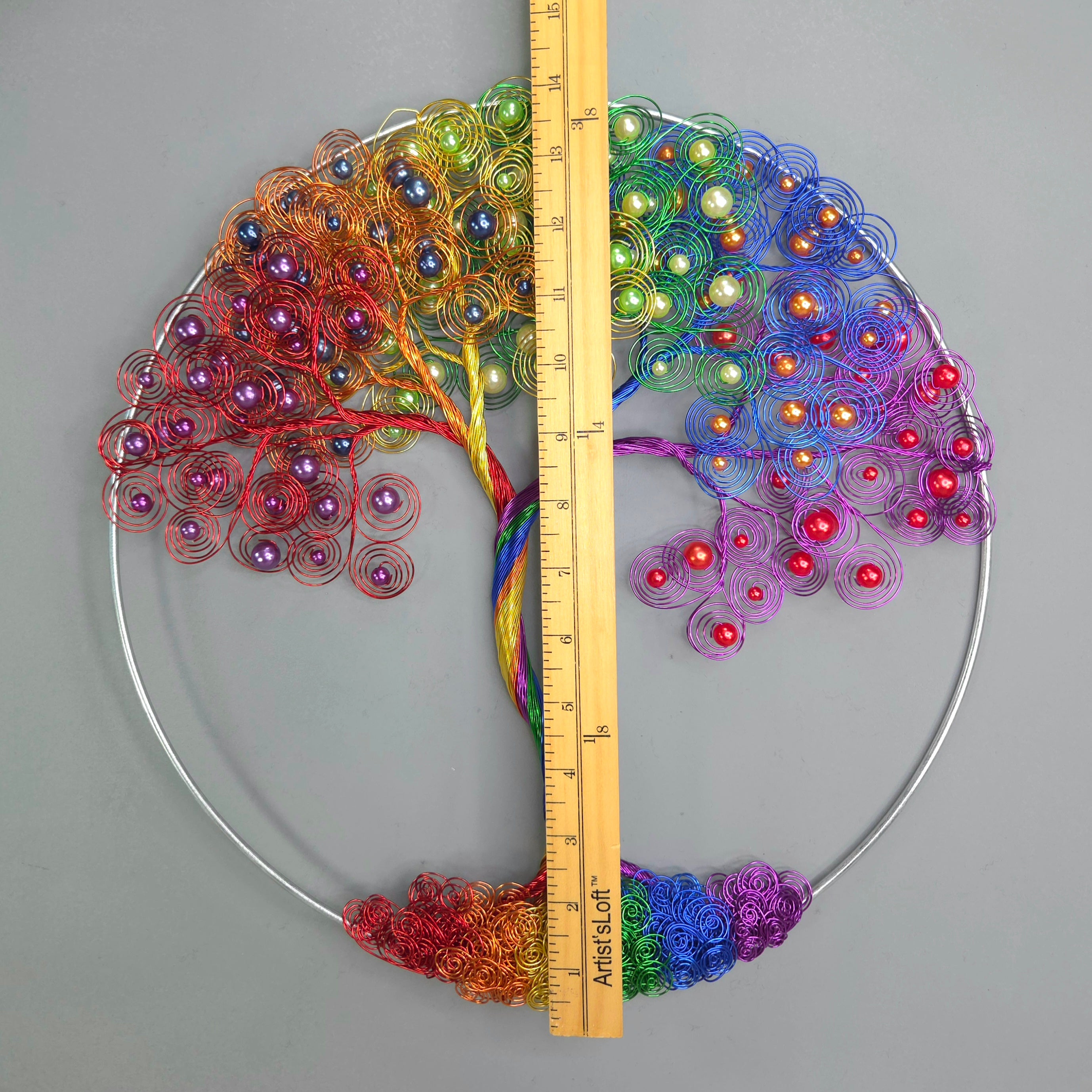 Colorful beaded tree of life art piece with a ruler for scale on a gray background