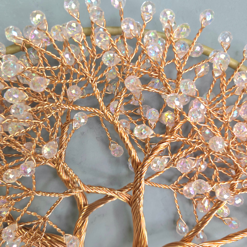 Decorative wall art with gold branches and crystal-like beads on a gray background