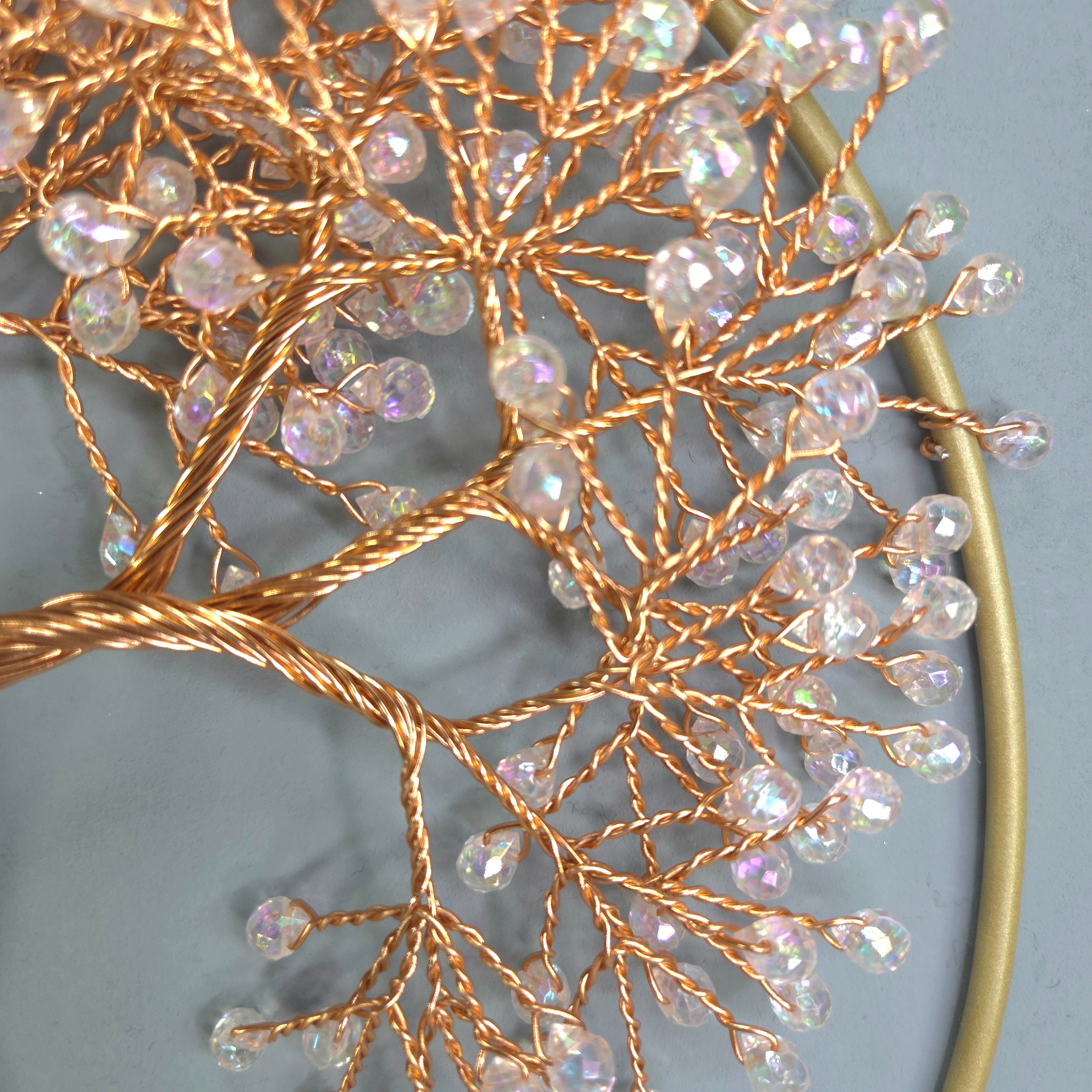 Decorative wall piece with gold branches and crystal-like beads on a gray background