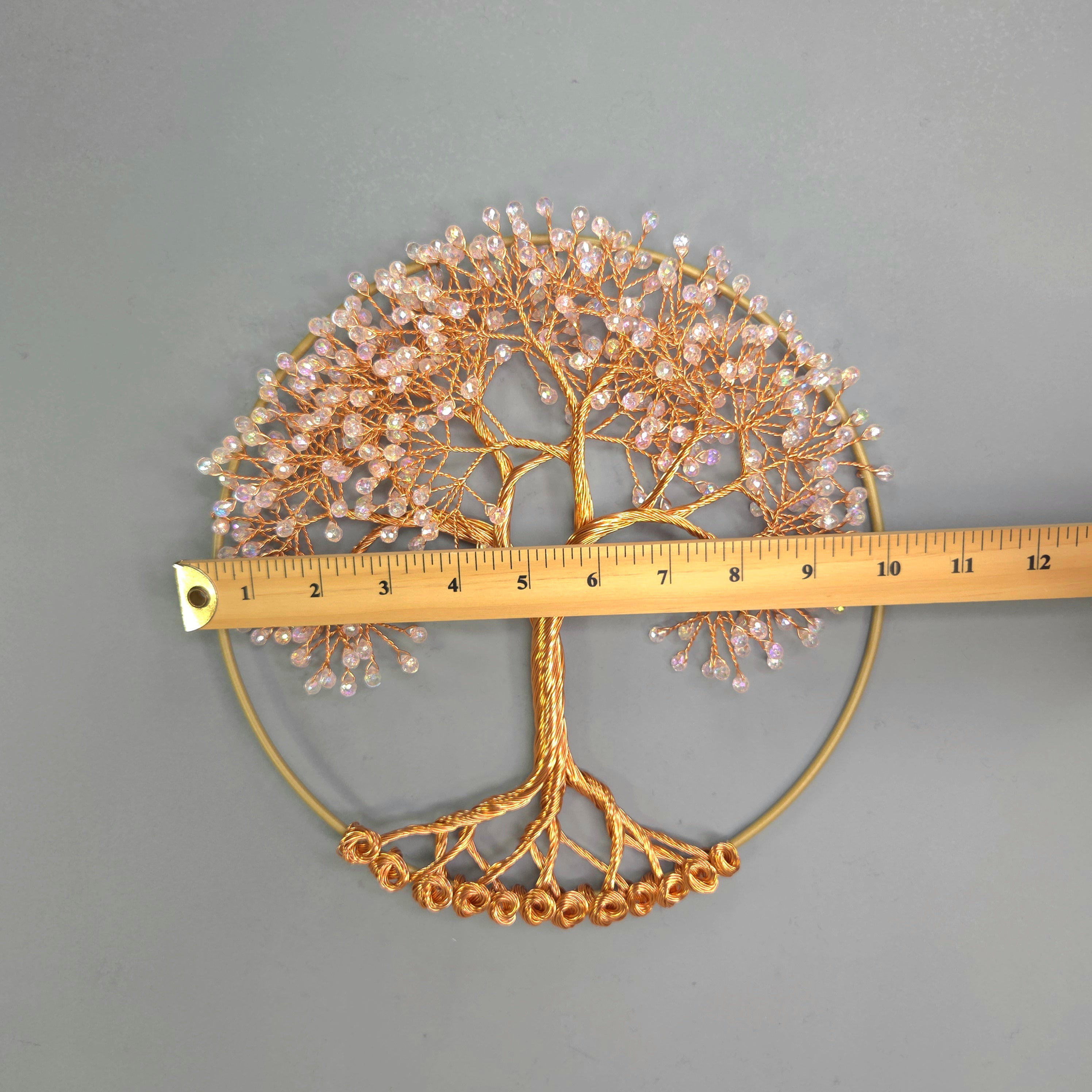 Decorative metal tree wall art with a ruler for scale on a gray background