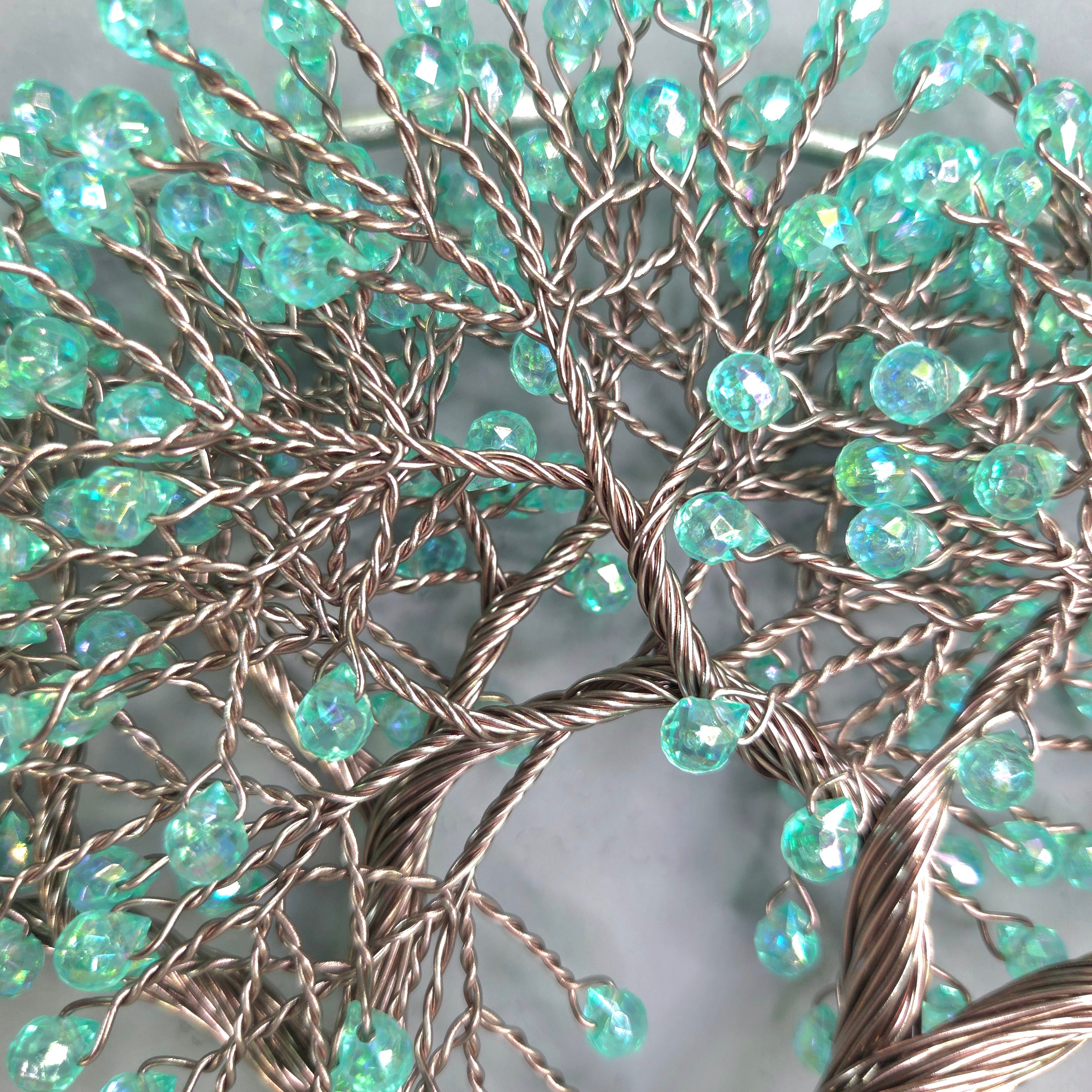 Decorative wall art with turquoise beads on a branch-like structure against a gray background