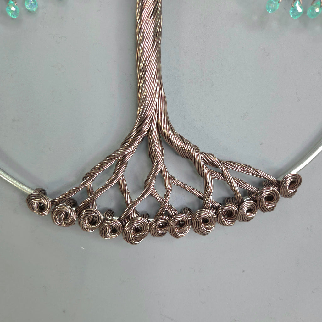 Close-up of a silver necklace with intricate design on a light gray background