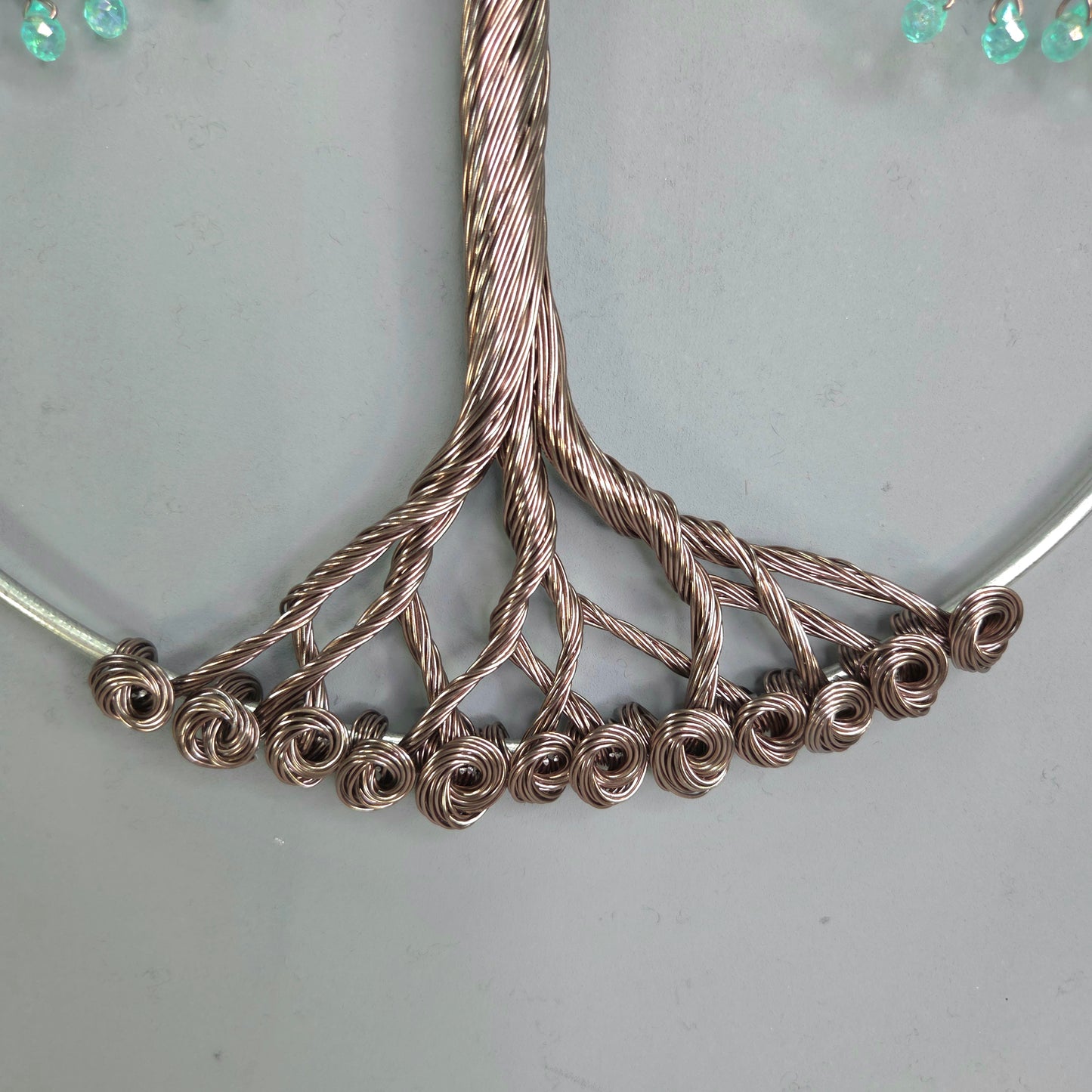 Close-up of a silver necklace with intricate design on a light gray background
