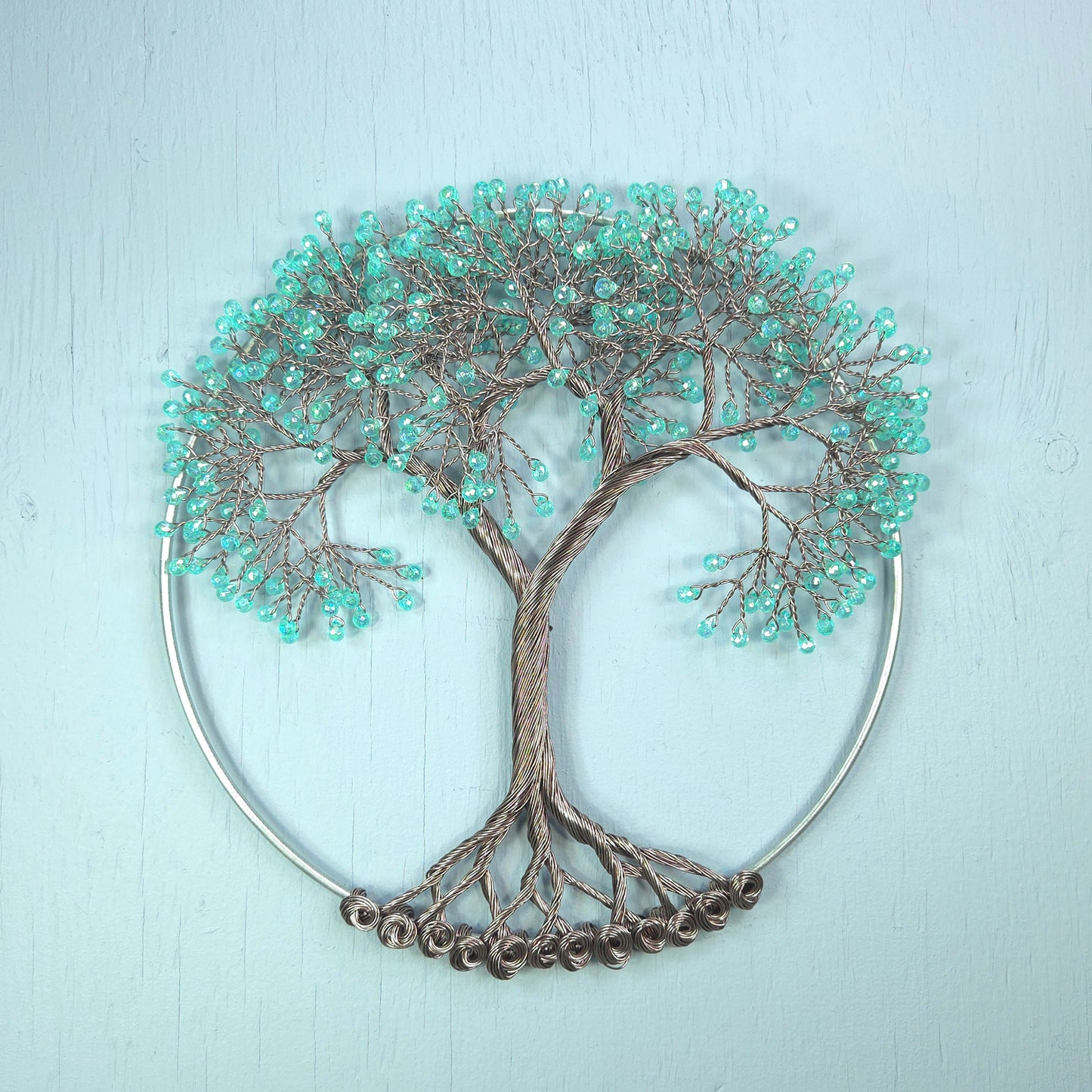 Decorative wall art of a tree with turquoise beads on a light blue background