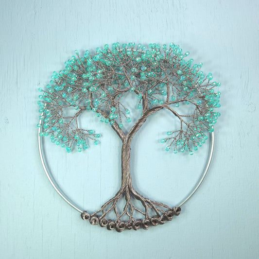 Decorative wall art of a tree with turquoise beads on a light blue background