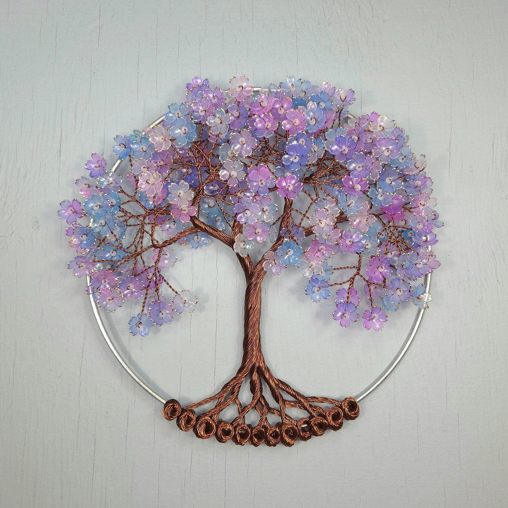 Decorative wall art of a tree with purple and blue beads on a light gray background