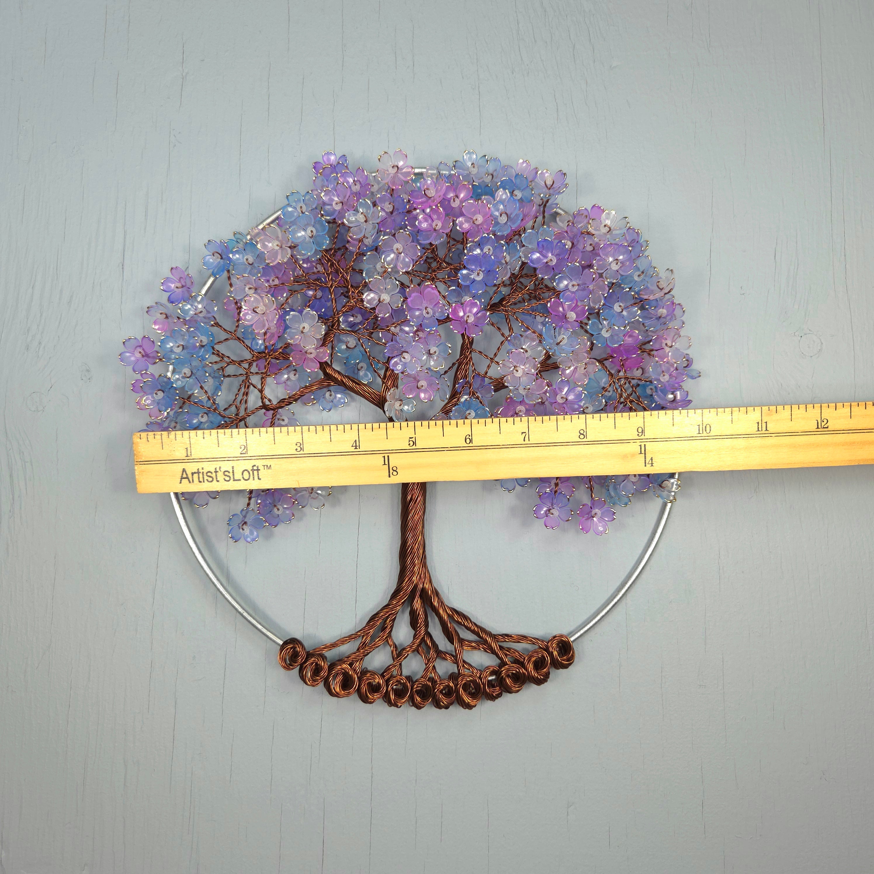 Decorative tree wall art with purple flowers and brown trunk, measured against a ruler on a gray background.
