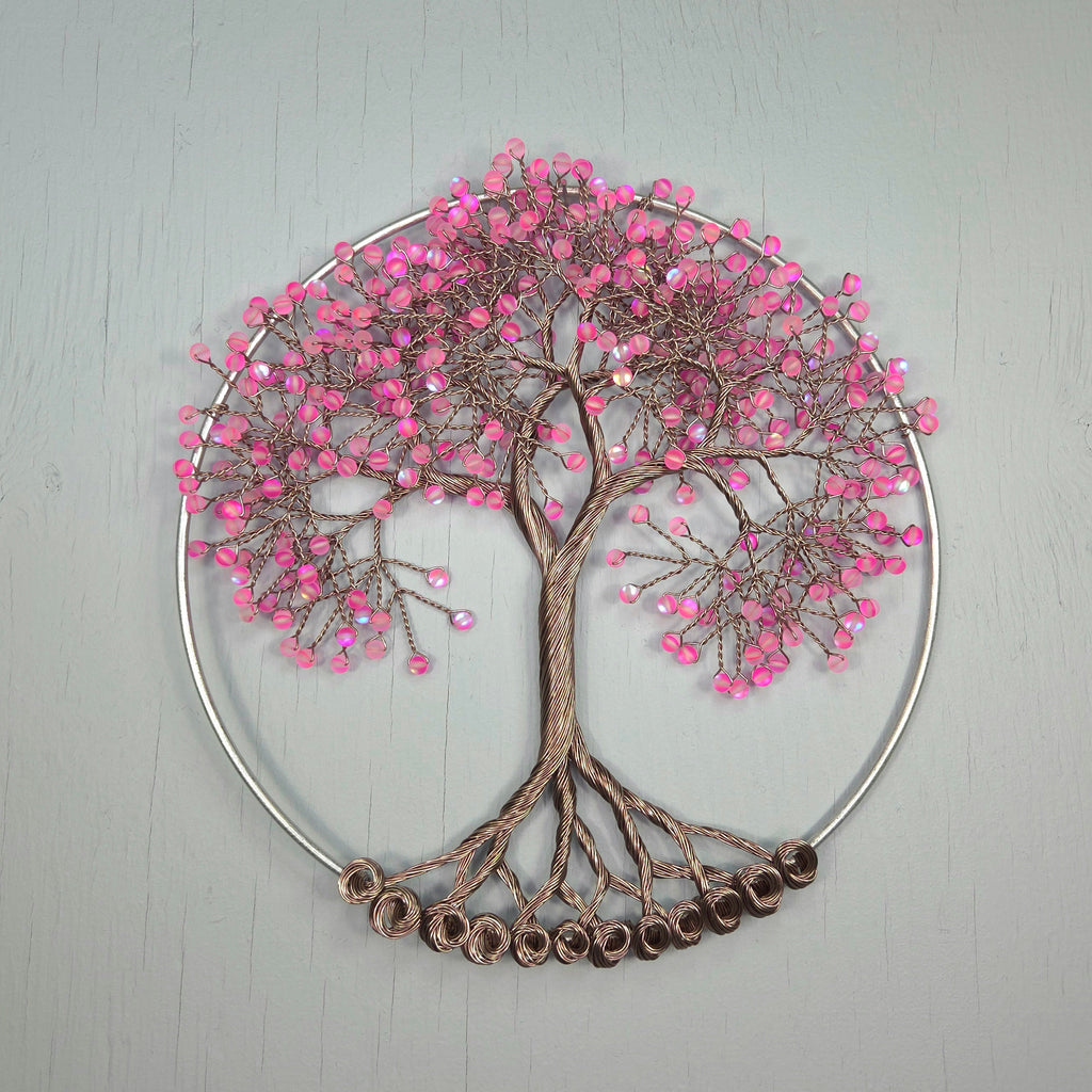 Decorative wall art of a tree with pink beads on a gray background