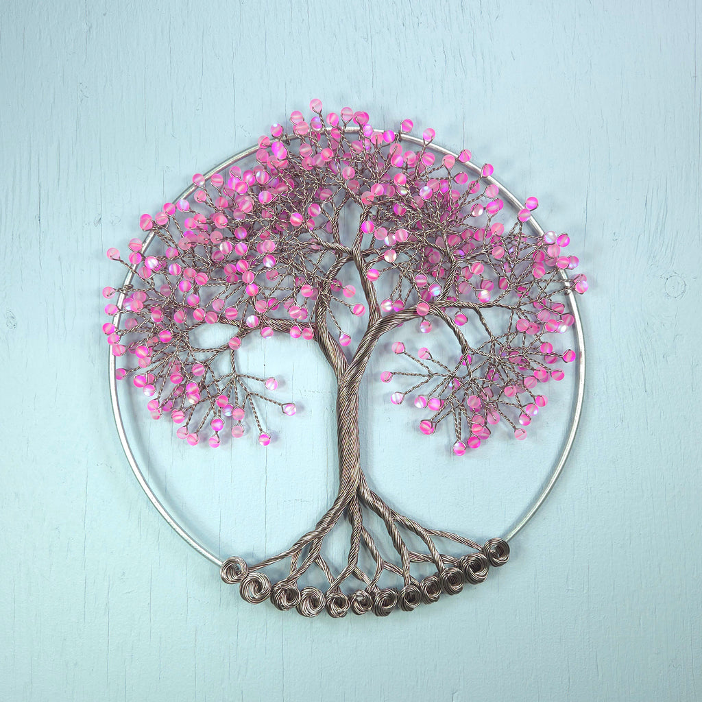 Decorative wall art in the shape of a tree with pink beads on a light blue background