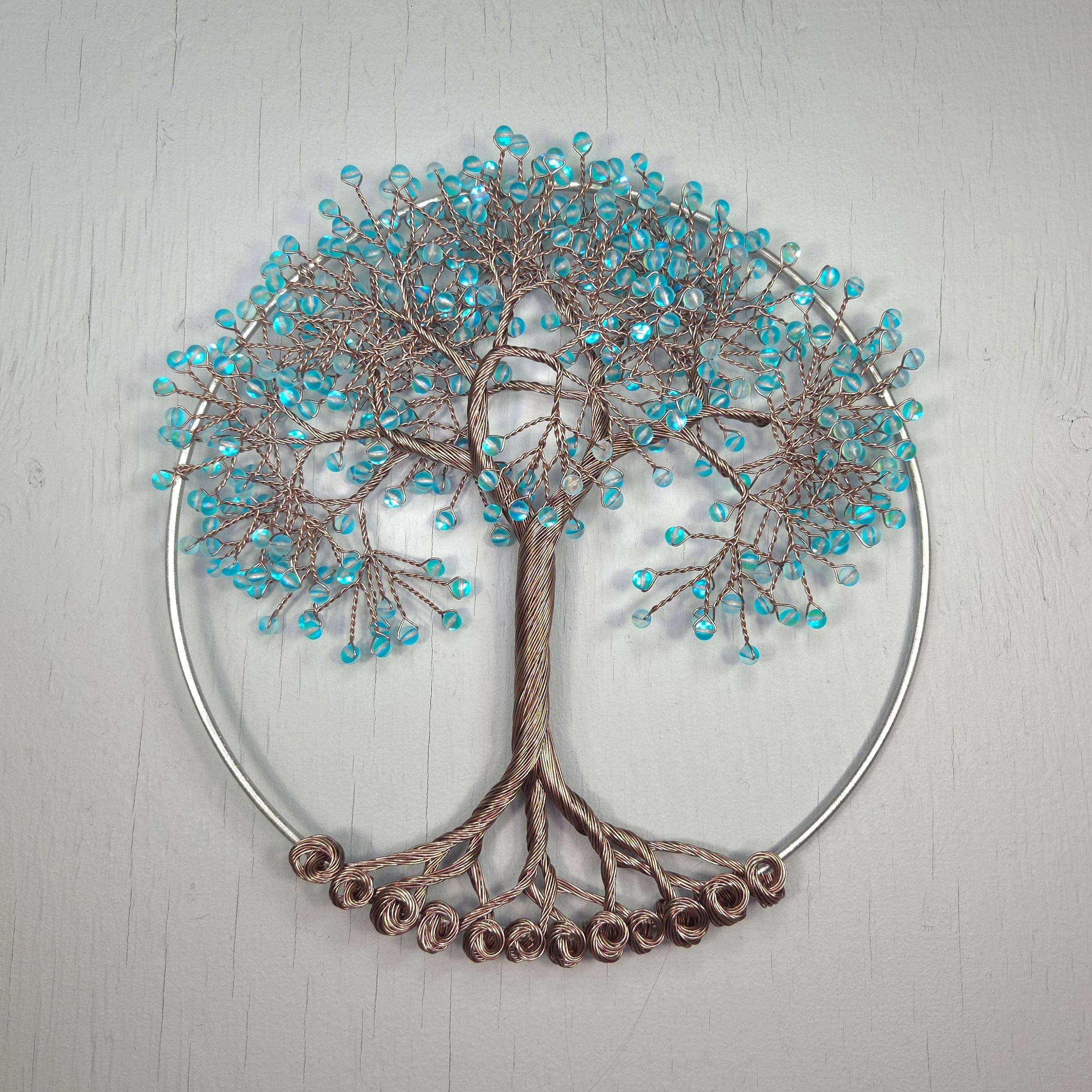 Decorative wall art of a tree with blue beads on a light gray background