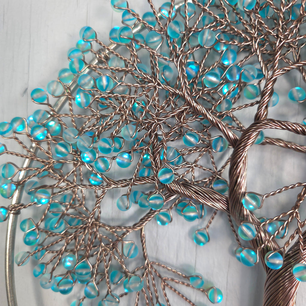 Decorative wall art with blue beads and bronze wire on a light background