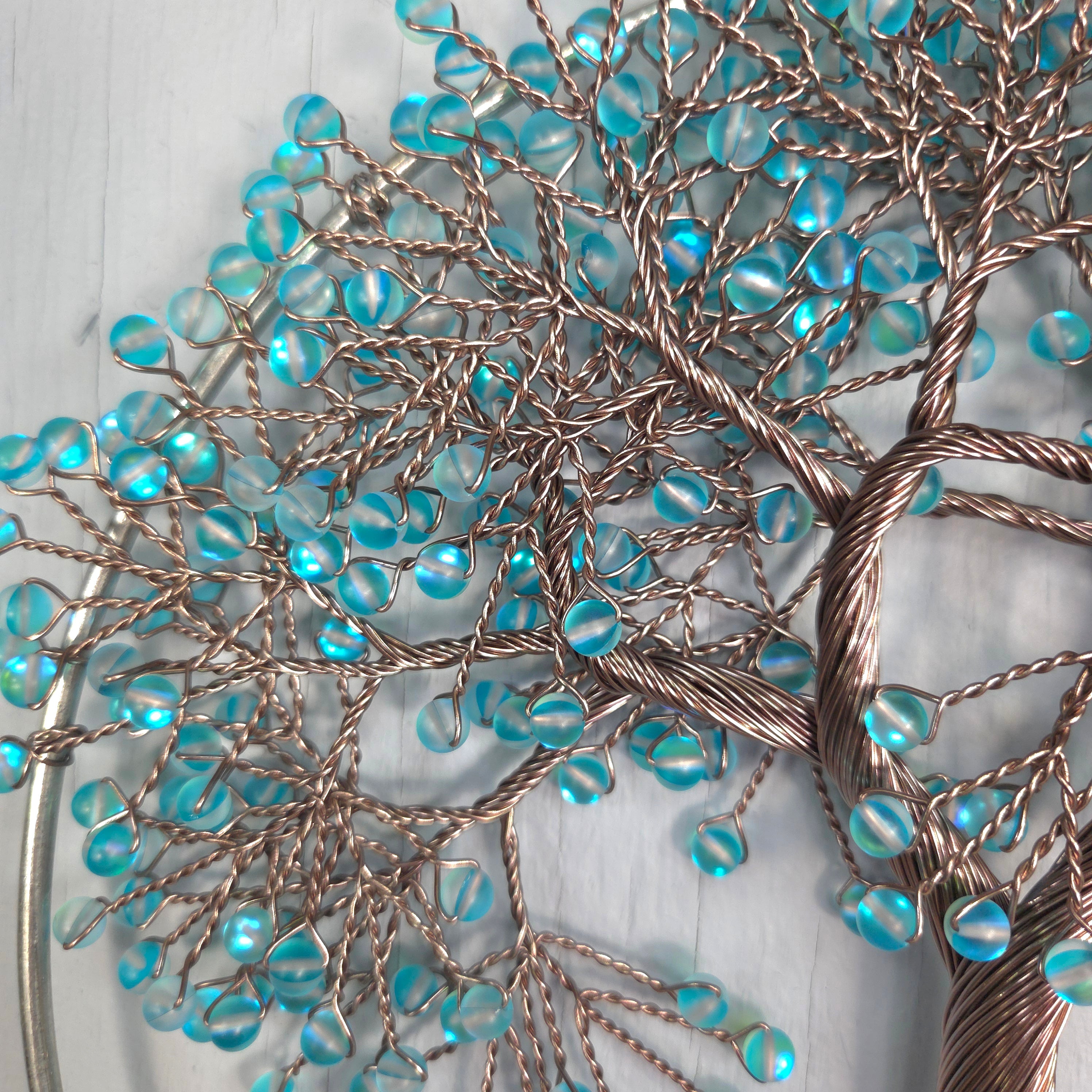 Decorative wall art with blue beads and bronze wire on a light background