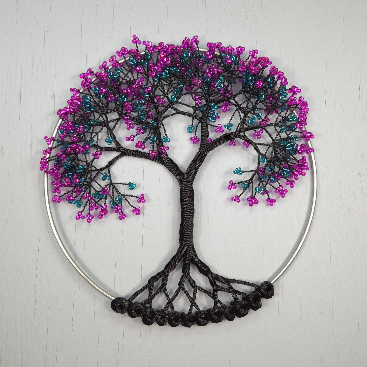 Decorative wall art with a tree design made of beads on a white background