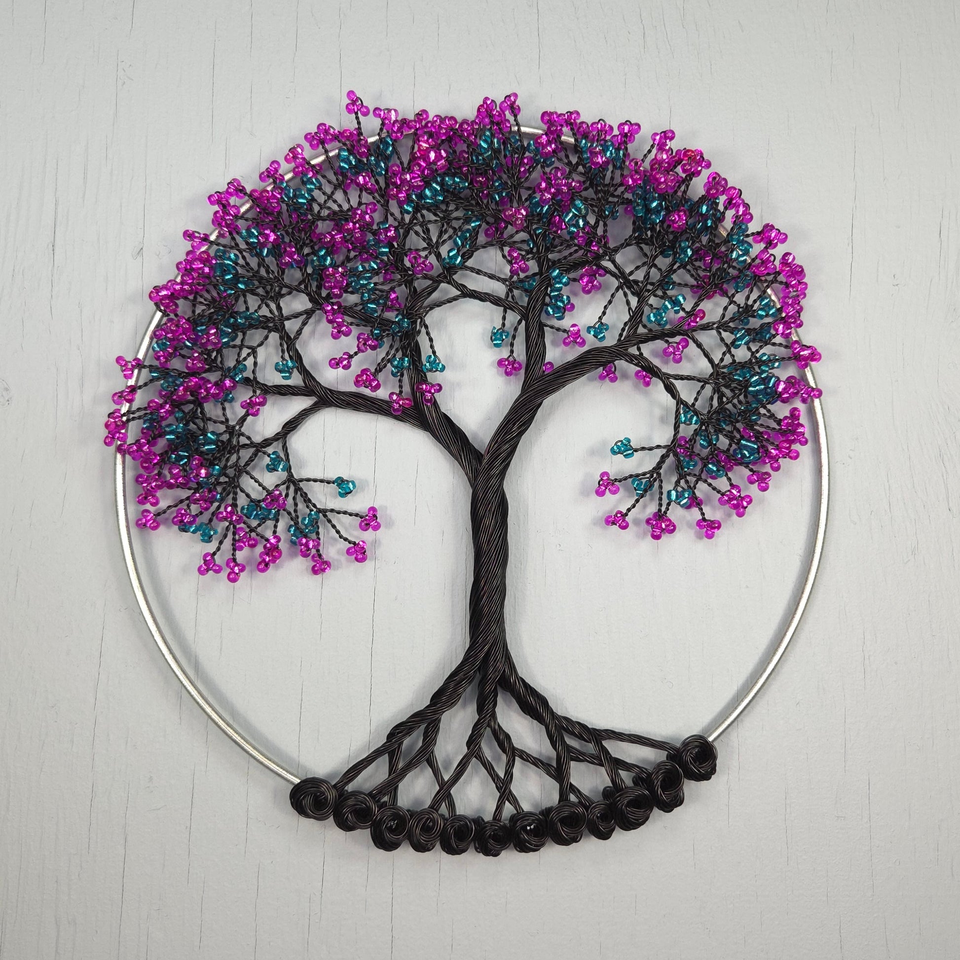 Decorative wall art with a tree design made of beads on a white background