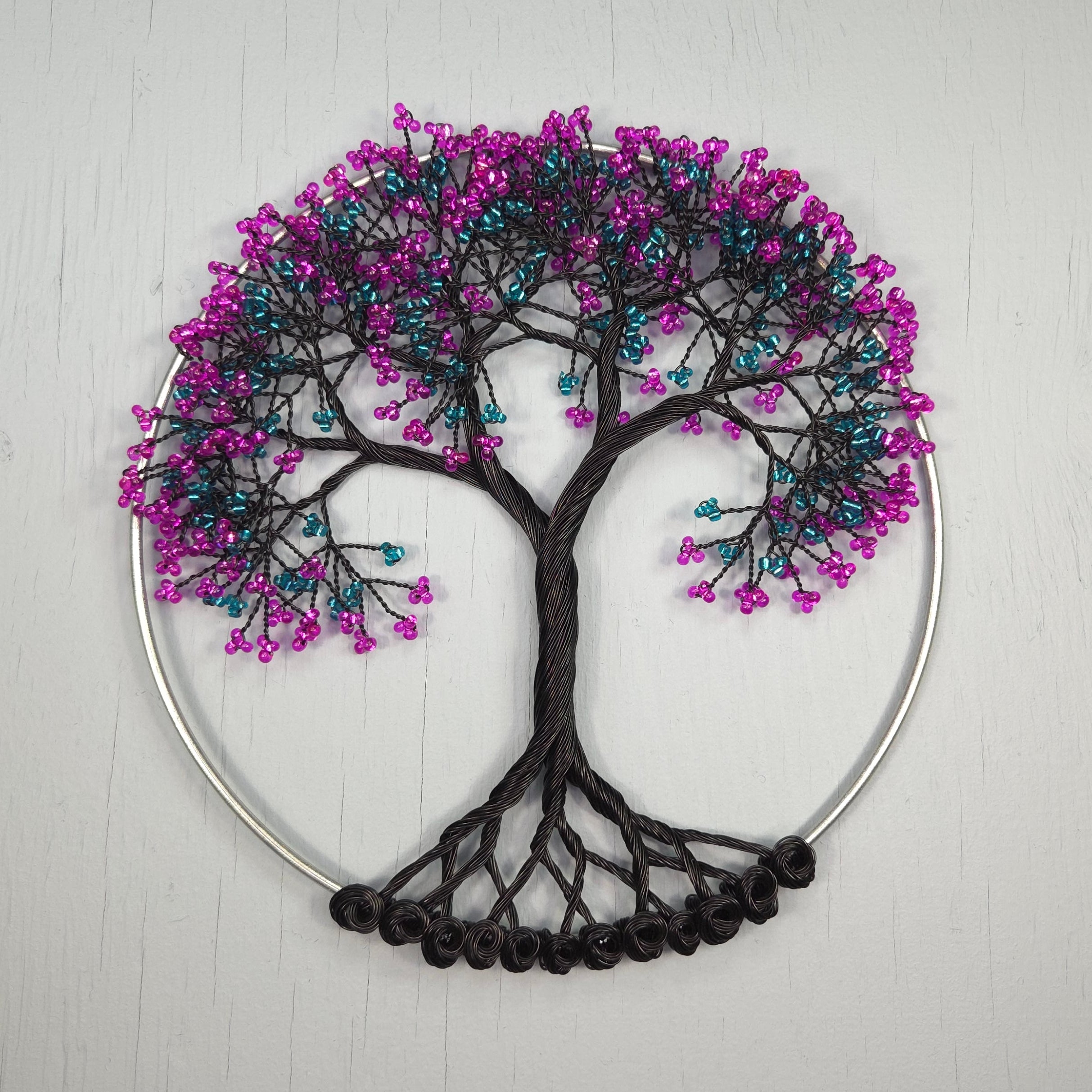 Decorative wall art with a tree design made of beads on a white background