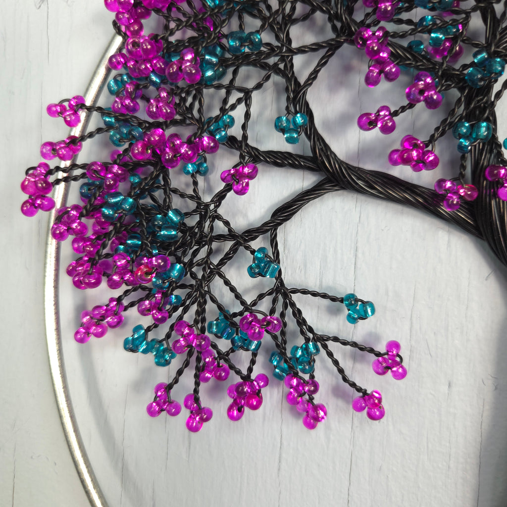 Decorative branch with purple and blue beads on a white surface