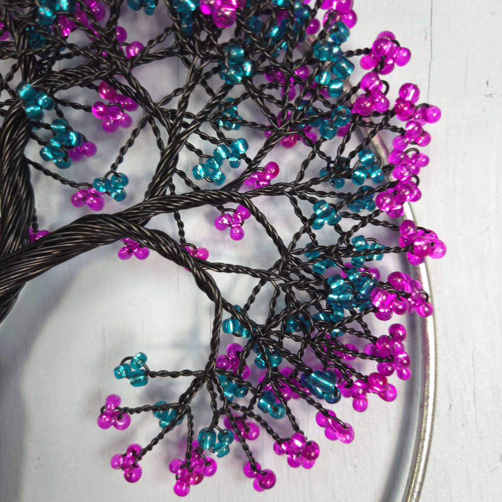 Decorative tree sculpture with pink and blue beads on a white background