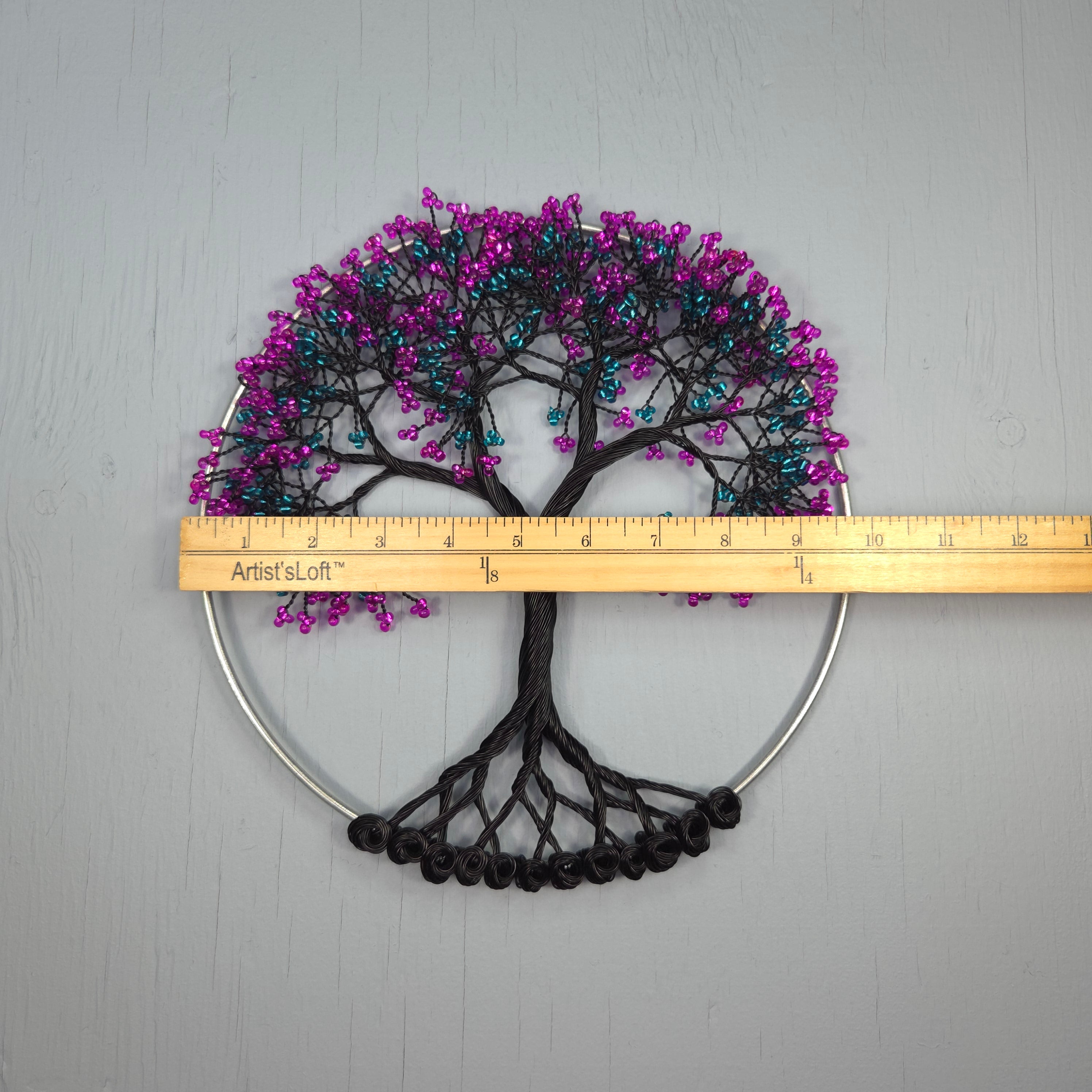 Decorative wall art with purple and black tree design on a gray background, measured by a ruler.