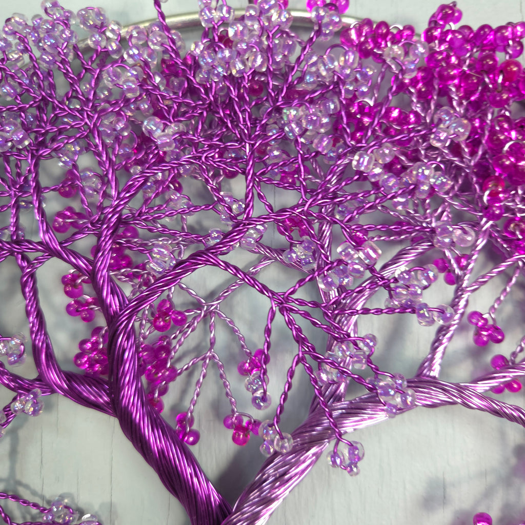 Close-up of purple decorative branch with beads on a light background
