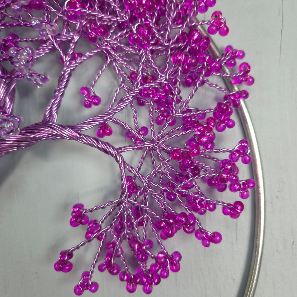 Decorative tree made of purple beads on a gray background