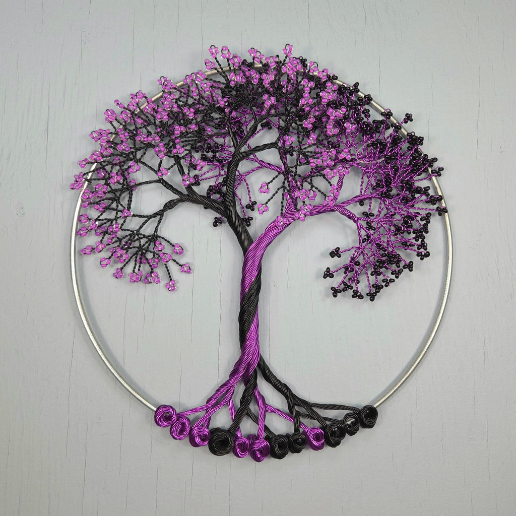 Decorative tree wall art with purple and black beads on a light gray background
