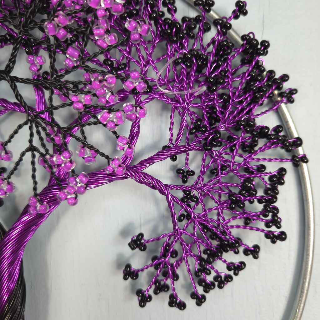 Decorative tree made of purple and black beaded branches on a white background