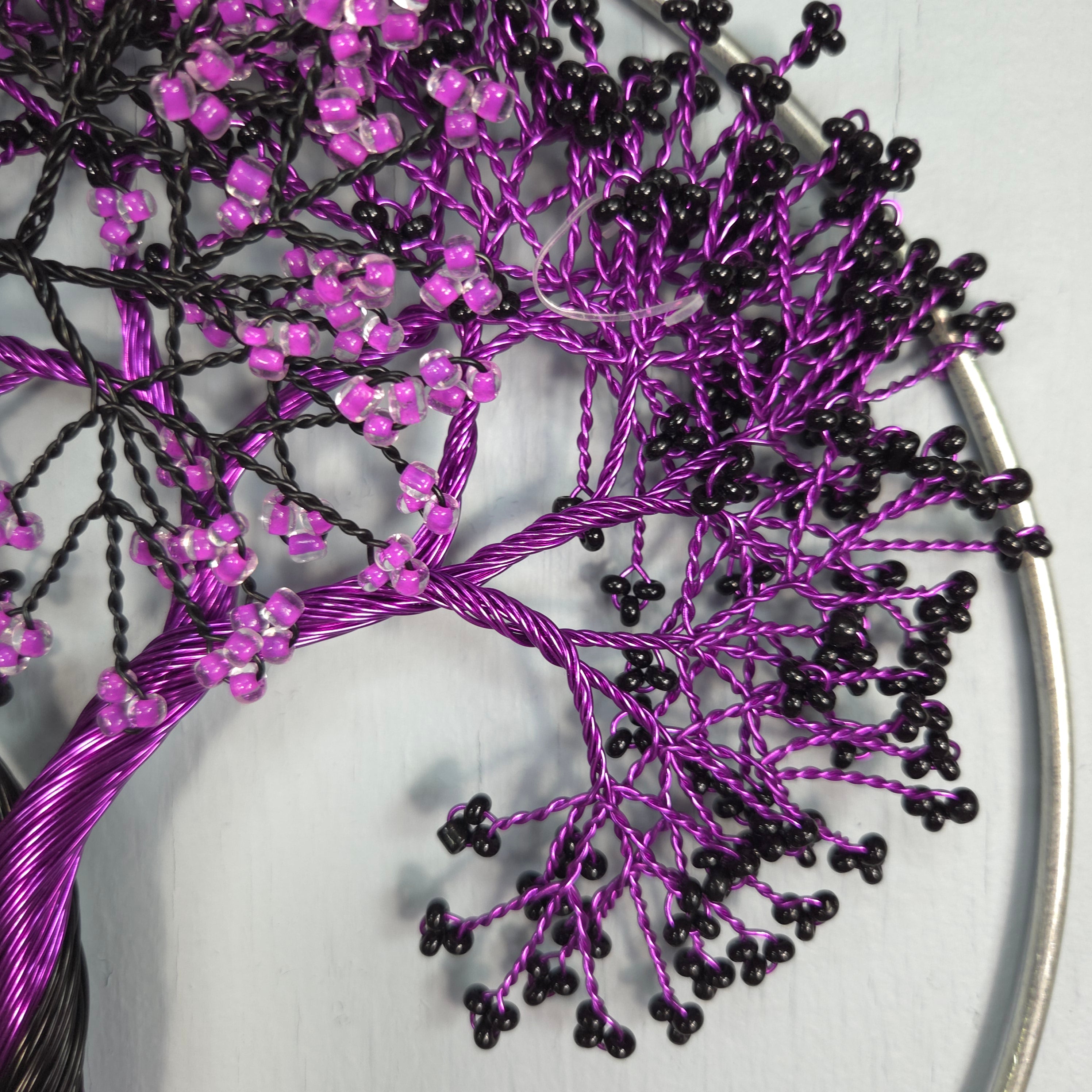 Decorative tree made of purple and black beaded branches on a white background