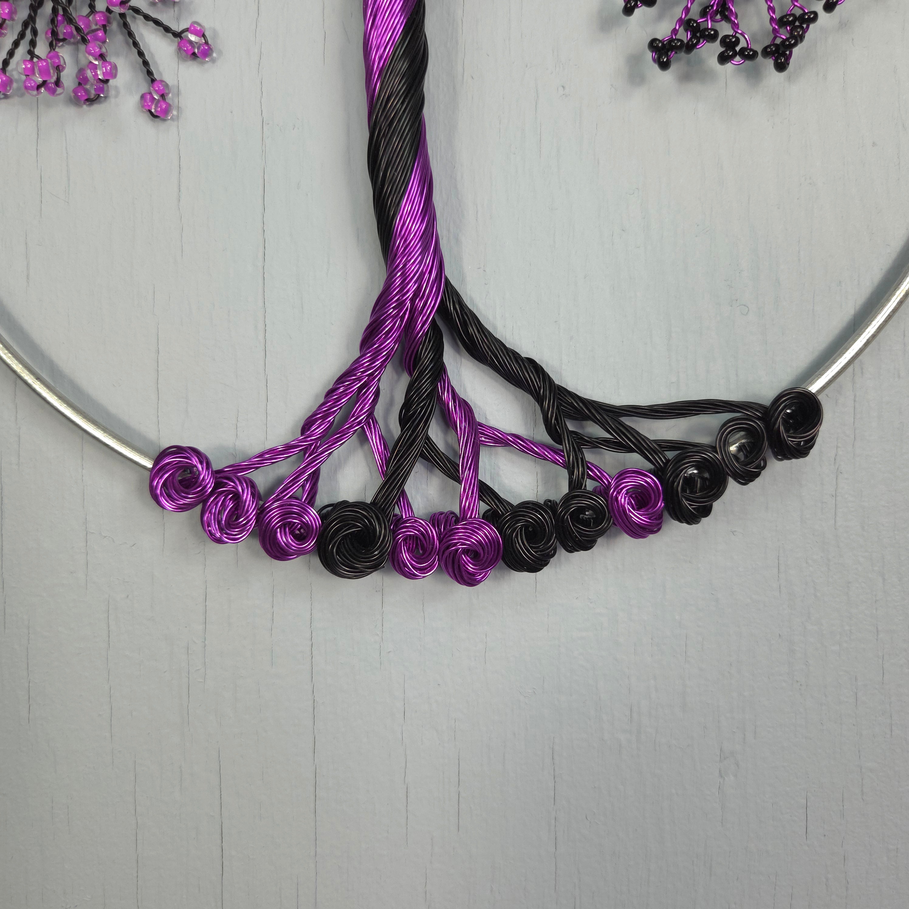 Necklace with purple and black floral elements on a light gray background