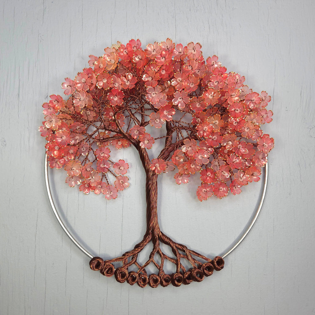 Decorative wall art of a tree with pink bead flowers on a gray background