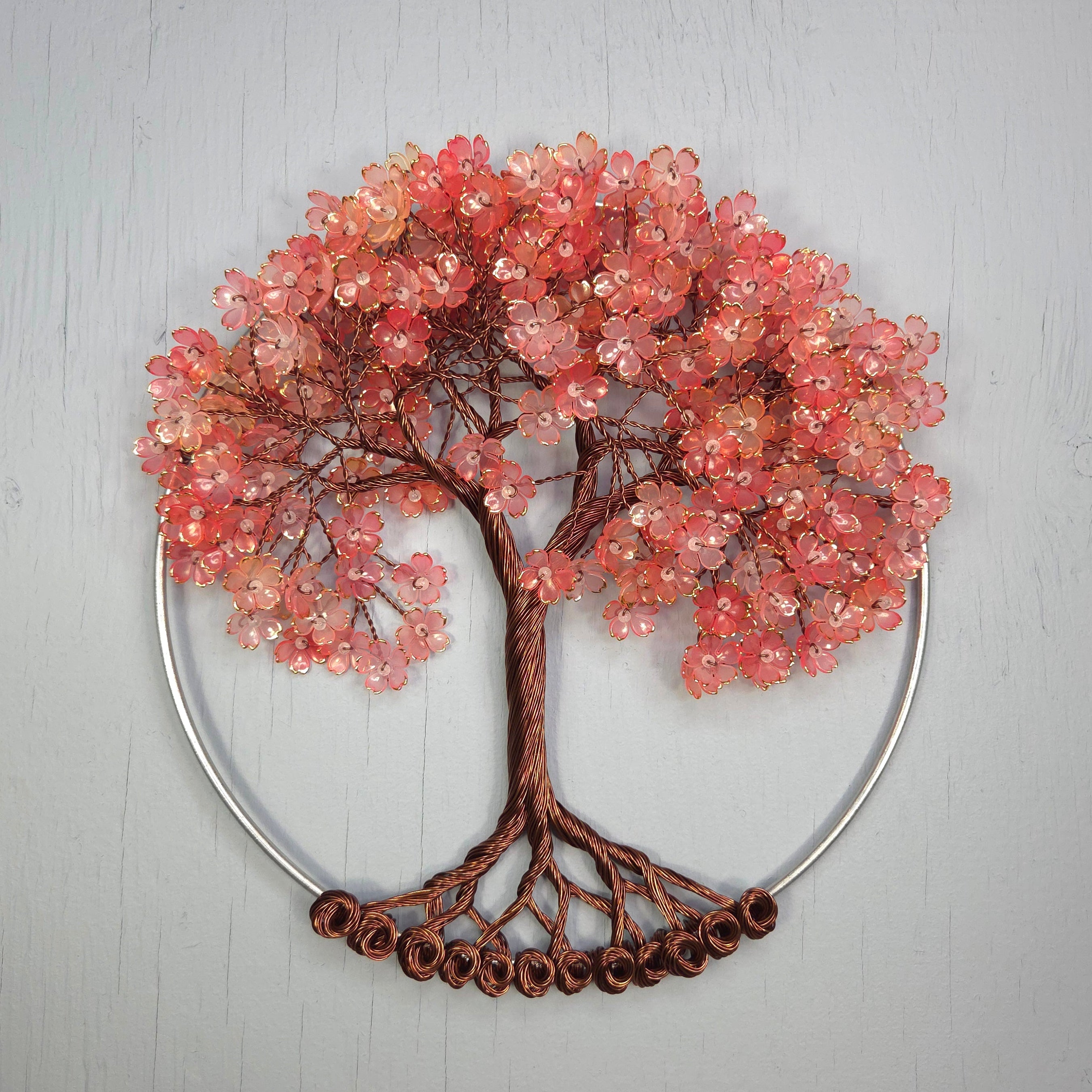 Decorative wall art of a tree with pink bead flowers on a gray background
