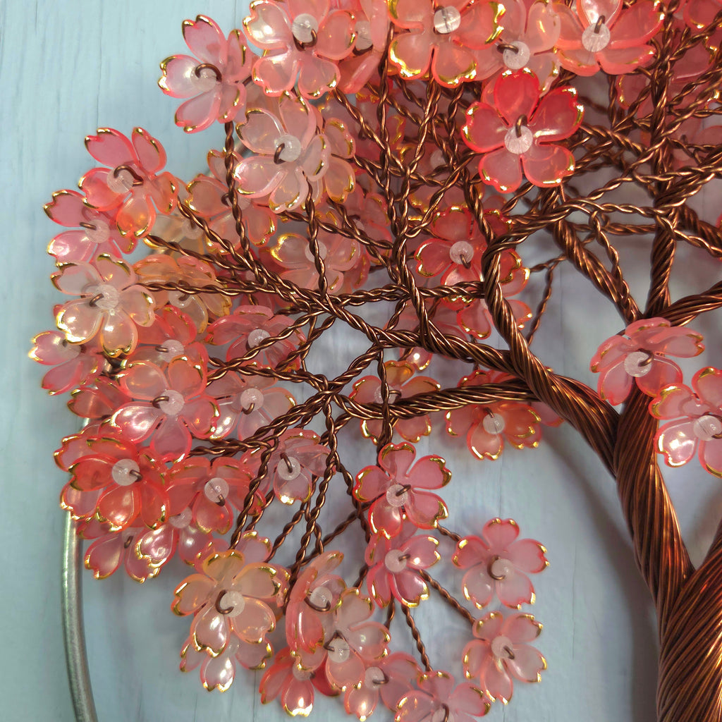 Decorative floral branch with pink flowers and copper branches on a light blue background
