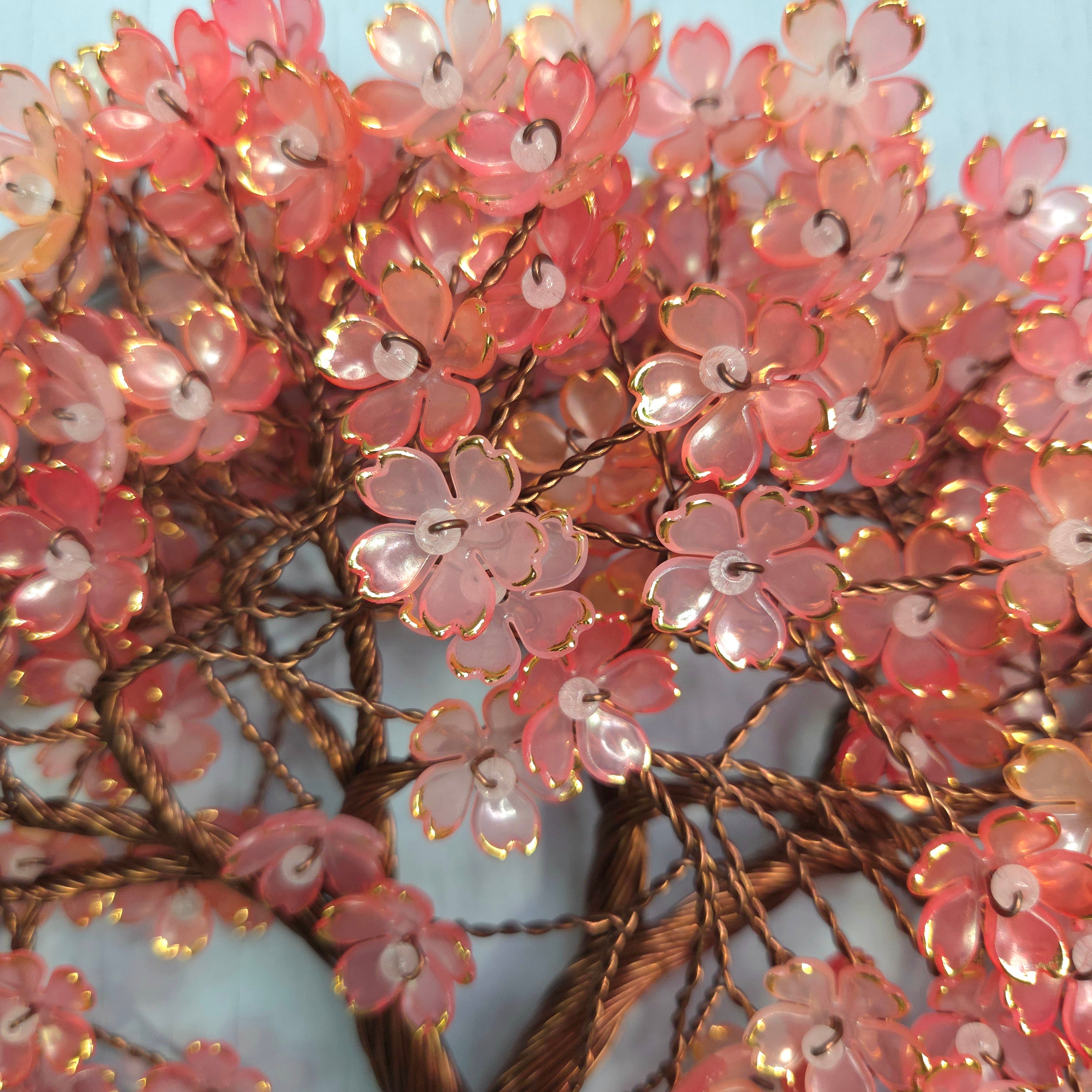 Decorative floral arrangement with pink flowers and gold branches on a light blue background