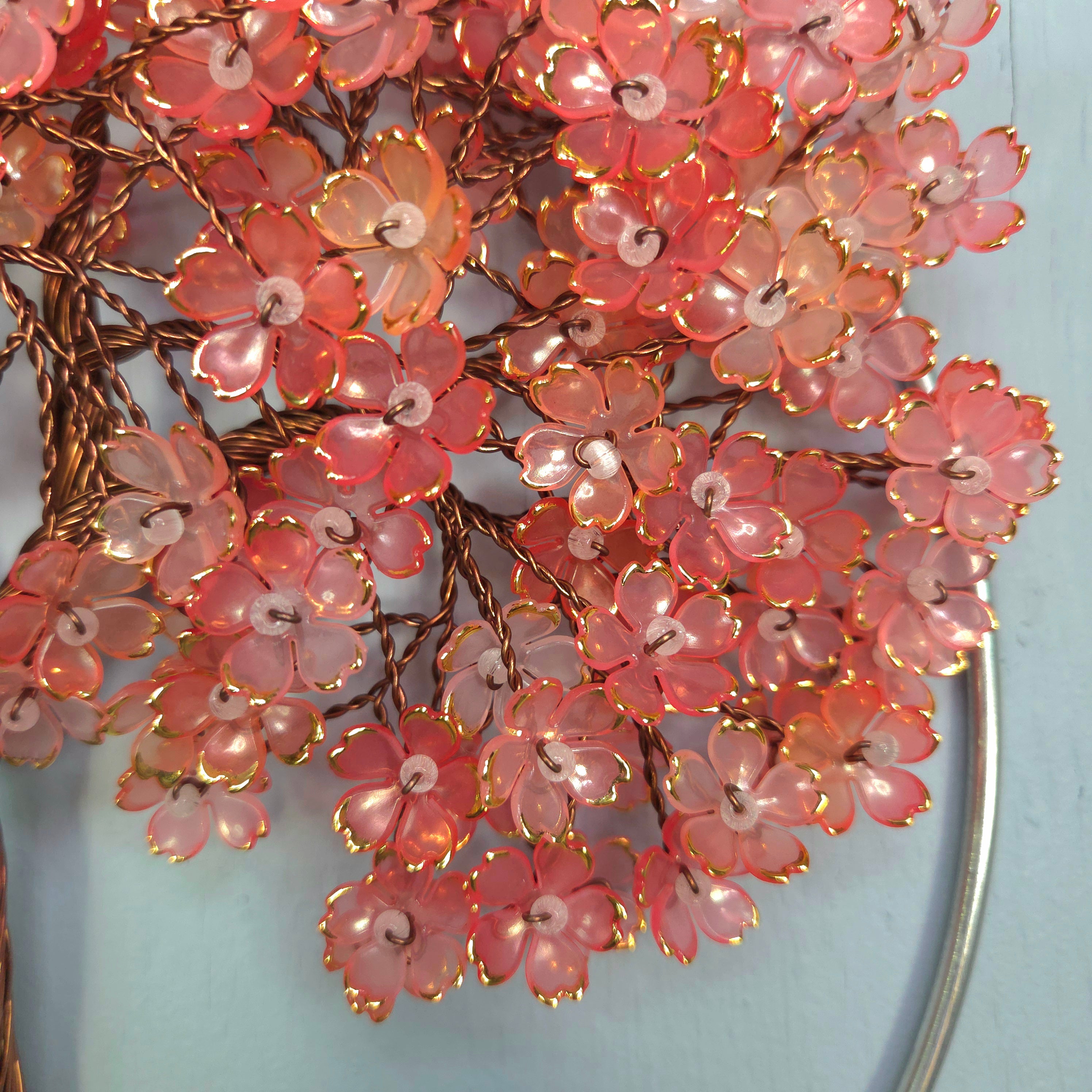 Decorative pink floral branch with gold accents on a light blue background