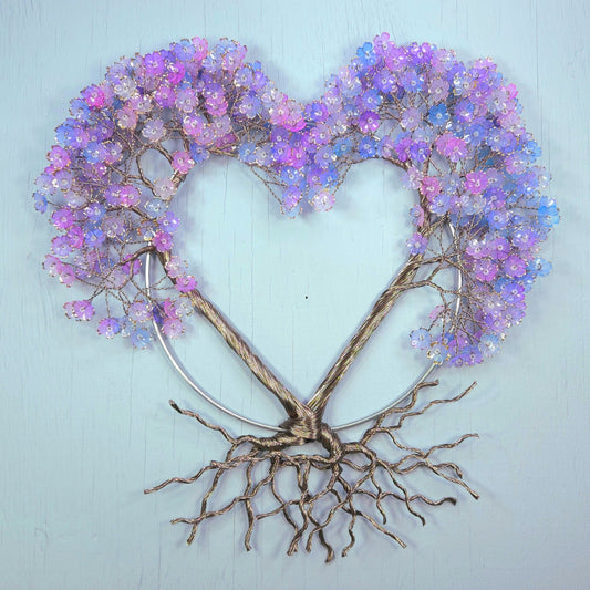 Decorative wall art with a heart shape made of branches and purple flowers on a light blue background.